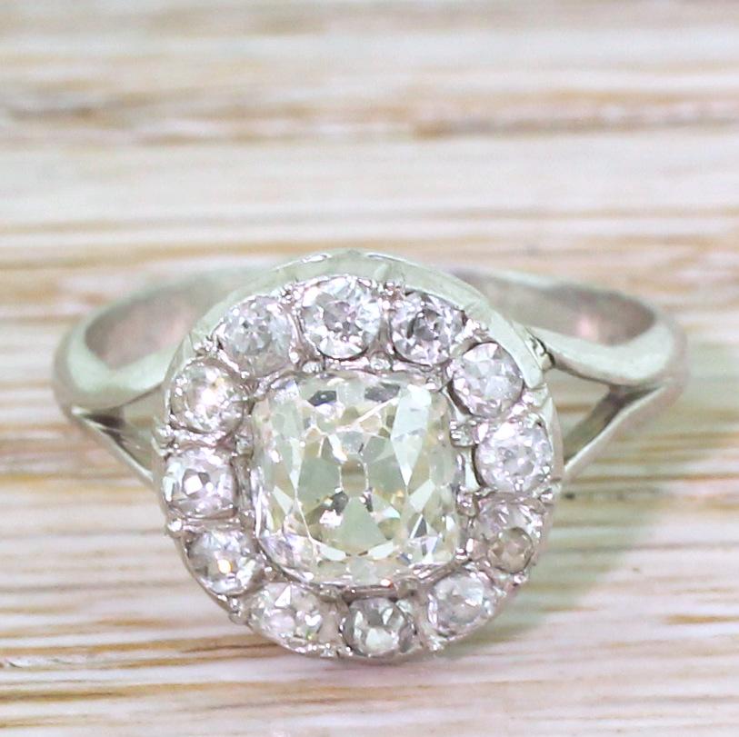 This sublime diamond cluster ring features a cushion shaped old mine cut in the centre which is internally clean and incredibly bright and lively. Twelve smaller old mine cut surround the centre within a simple double gallery, leading to
