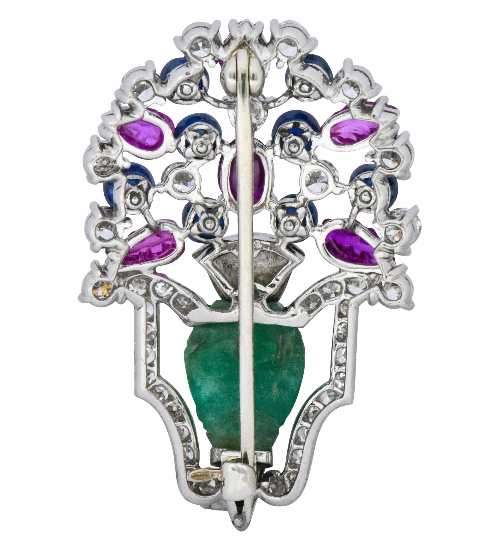 Designed as a bouquet of flowers in a carved emerald vase with black onyx detail

With foliate and floral carved rubies and carved bead sapphire ‘berries’

Accented by round brilliant, single, old European and straight baguette cut diamonds,