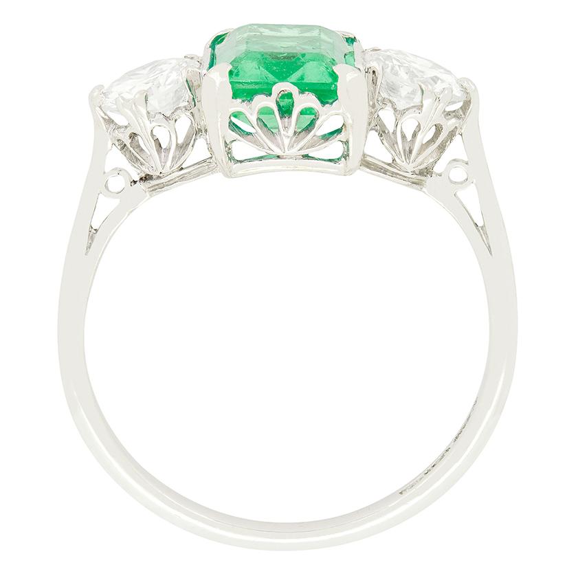 In this stunning Art Deco trilogy ring a large and vibrant emerald sits between two glittering old cut diamonds. This ring is set apart by its partiularly beautiful fluted fan like basket work, adding to the iconic Deco look of this ring. The 1.70
