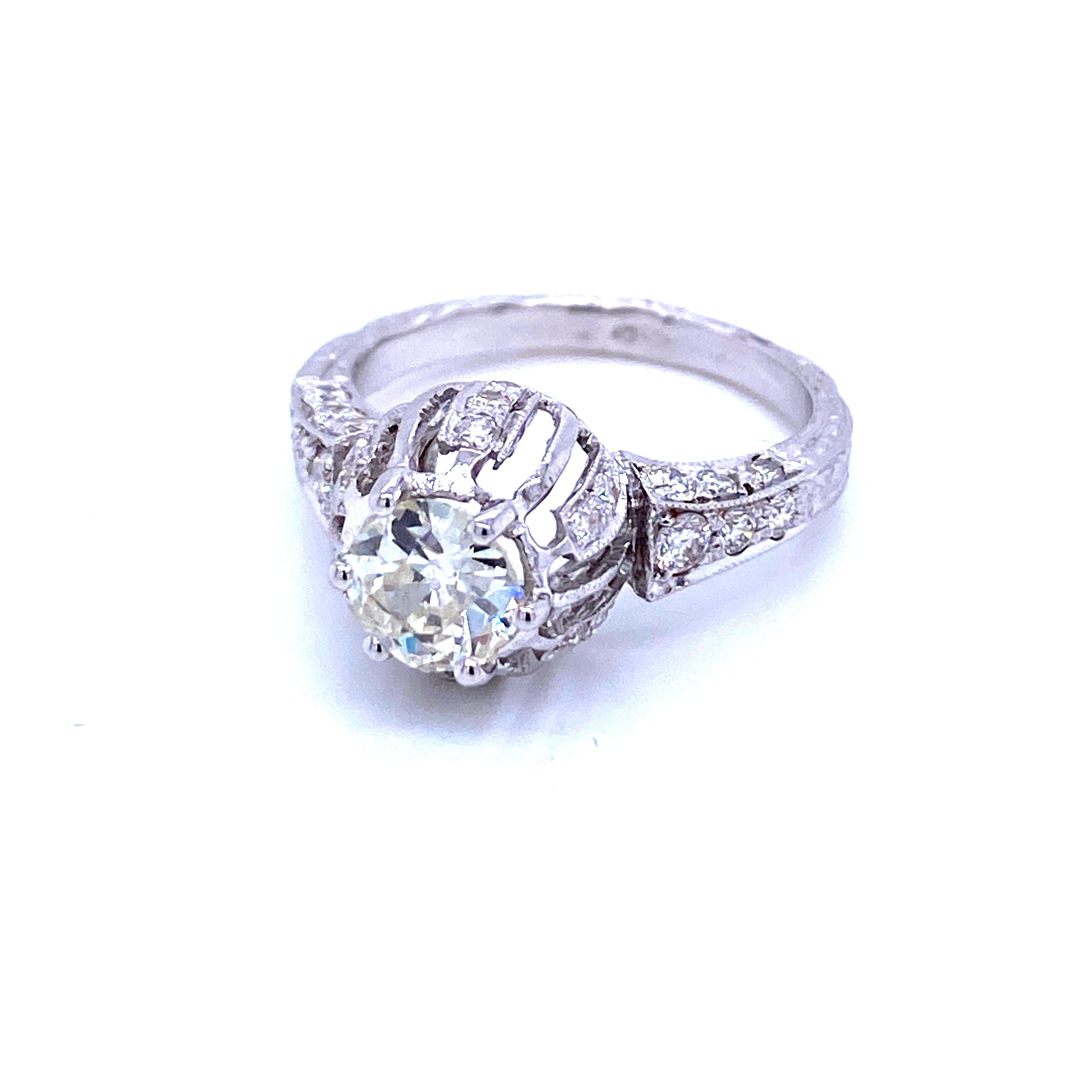 An exquisite example of Art Deco engagement ring, it is hand-crafted in 18k white gold, authentic from 1920/1930, featuring in the center a sparkling  Old mine-cut Diamond weighing approx. .90 carats, graded H/I color Vs1 clarity, framed by 0.85