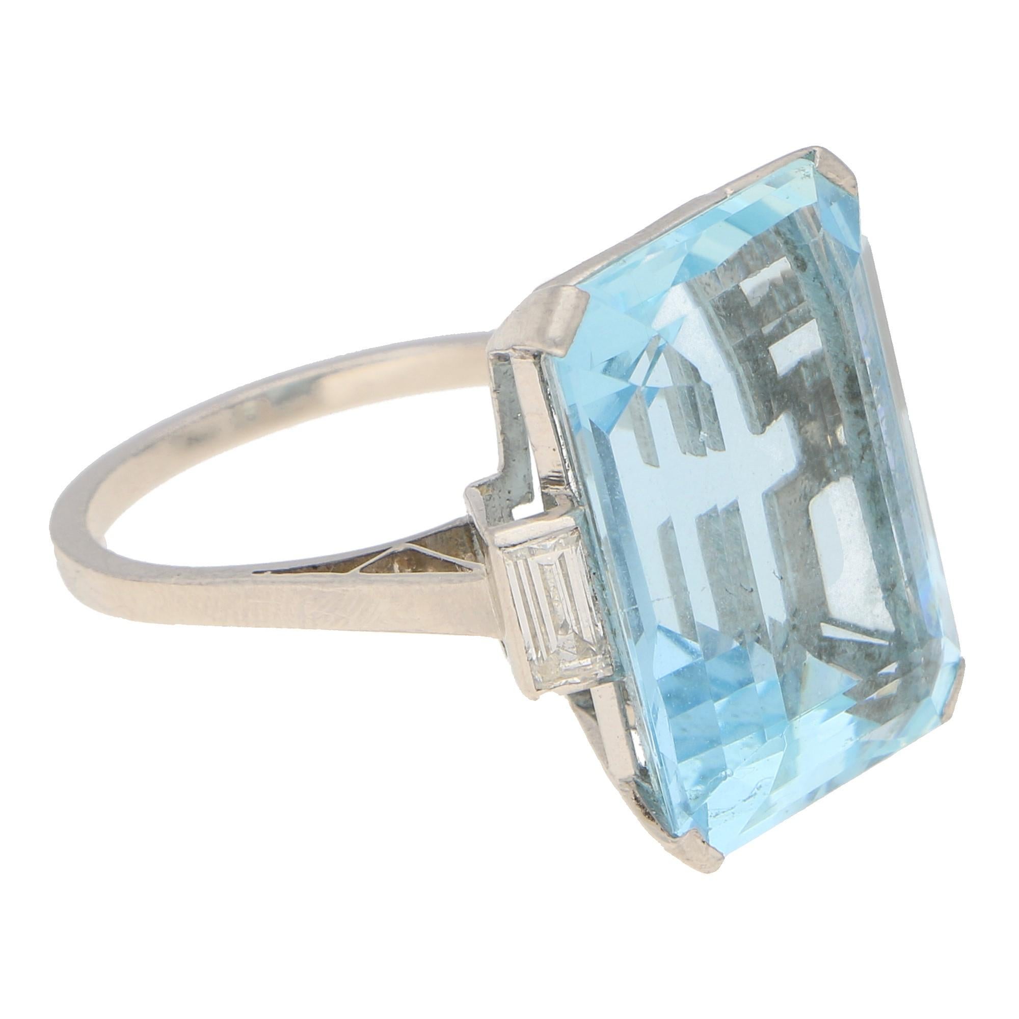 Aquamarine approximately 17 carats. Diamonds approximately 0.40 carats, G/H colour, SI clarity.
An Art Deco aquamarine and diamond cocktail ring in platinum featuring a large emerald-cut aquamarine four-claw-set to the centre, flanked to each side