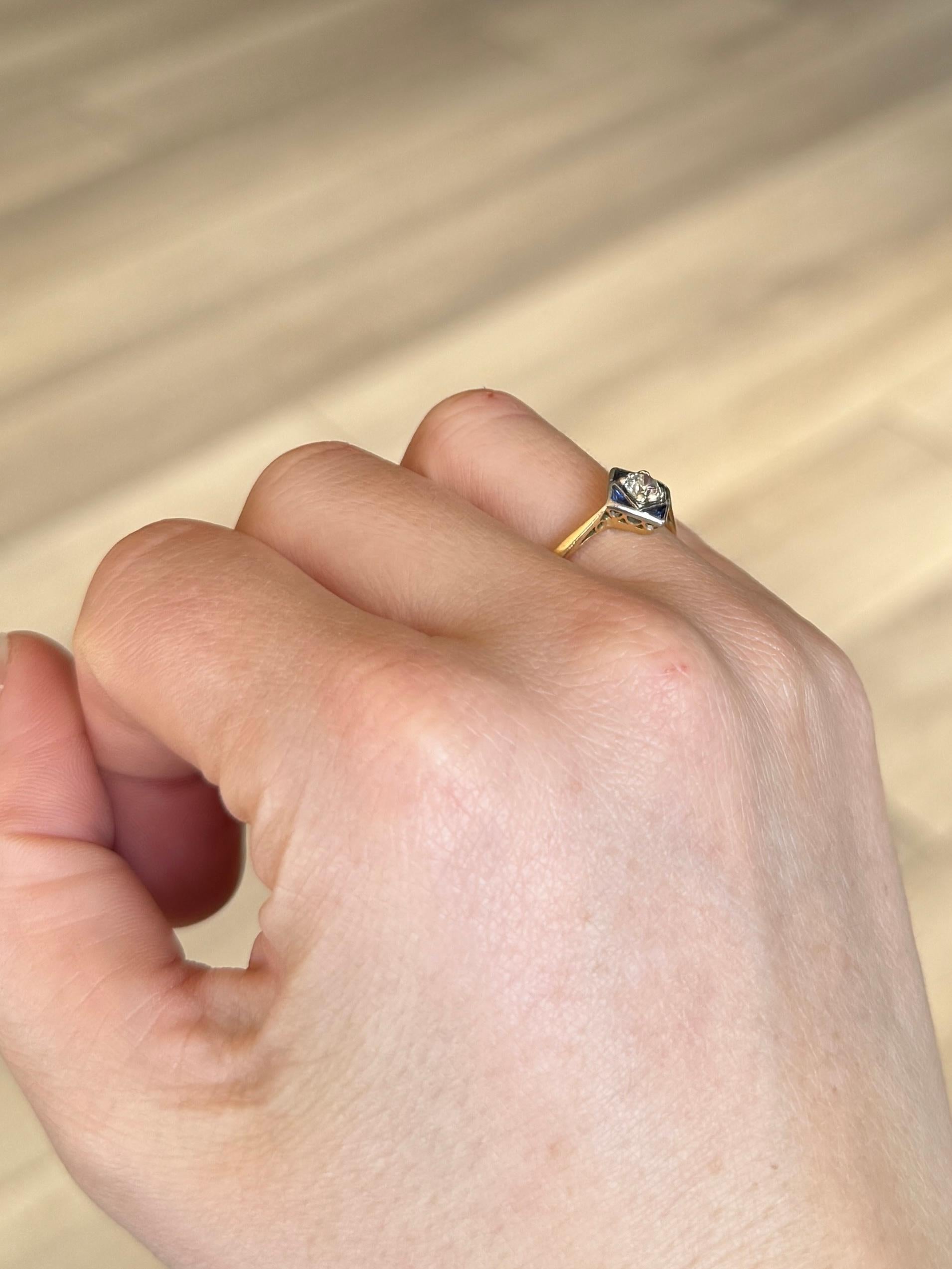 Questo squisito anello a pannello Art Deco è incastonato al centro con un brillante diamante. Il diamante misura 40 carati e gli zaffiri blu intenso completano perfettamente la pietra scintillante. L'anello è realizzato in oro 18 carati e le pietre
