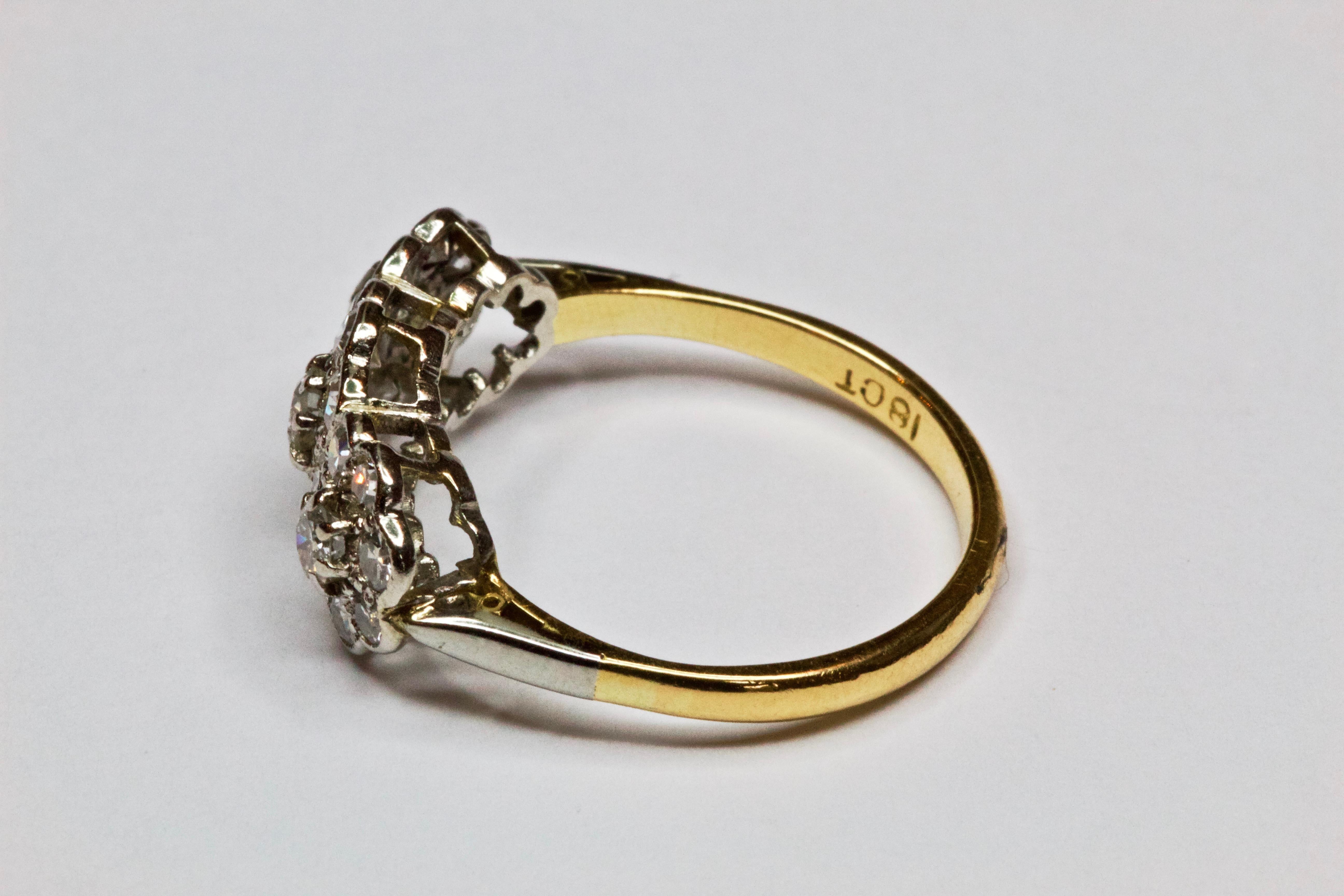 An antique triple cluster diamond ring, three old cut diamonds, surrounded by a triple cluster of old cut diamonds, diamonds set in platinum with platinum doubled shoulders on an 18ct yellow gold band 

Ring Size O or 7 
