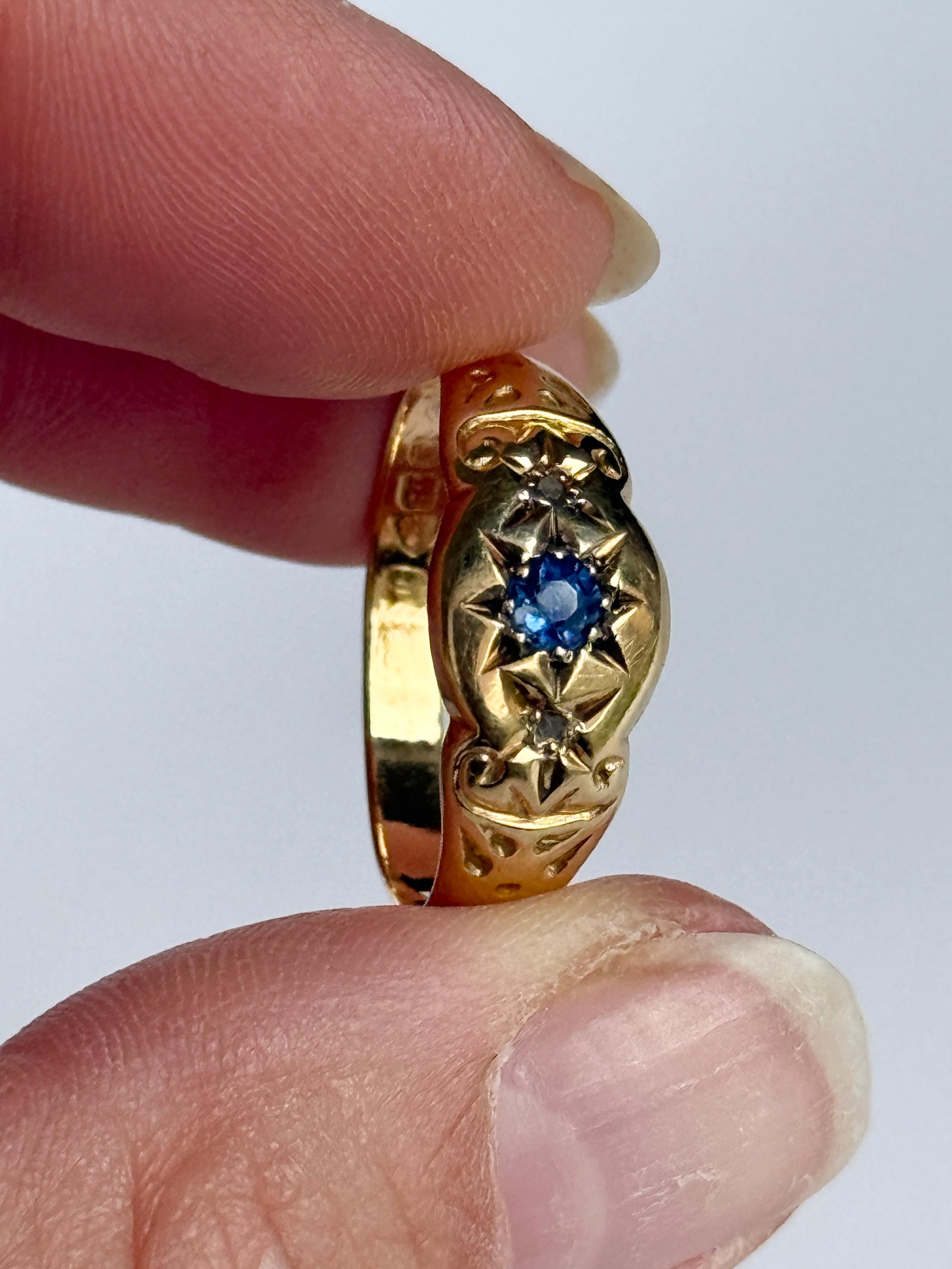 This ring holds a sapphire at the centre measuring approx 15pts and two rose cut diamonds measuring 2pts each. These are set in star settings. Fully hallmarked Chester 1919. 

Ring Size: R or 8 1/2
Band Width: 9mm

Weight: 2.2g