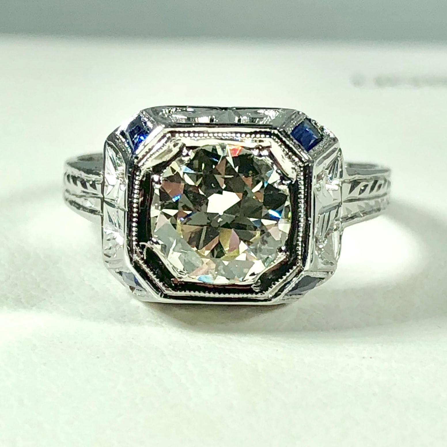 Art Deco 18 karat 1.40 carat European cut diamond and sapphire engagement ring. This true Art Deco piece is a work of art. Created in 18 karat white gold weighing, 3.8grams, 2.4 dwt. Filigree cut out design build up the dome centerpiece. The light