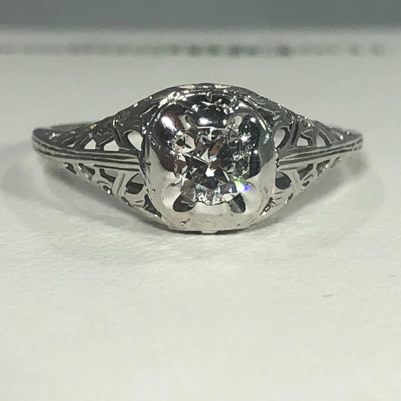 Art Deco 18 karat and old European cut diamond solitaire engagement ring. This is a true antique Art Deco ring, Circa 1925. This piece is created in 18 karat white gold, beautiful cut out filigree design, weighing 1.7 grams, 1.1 DWT. The center