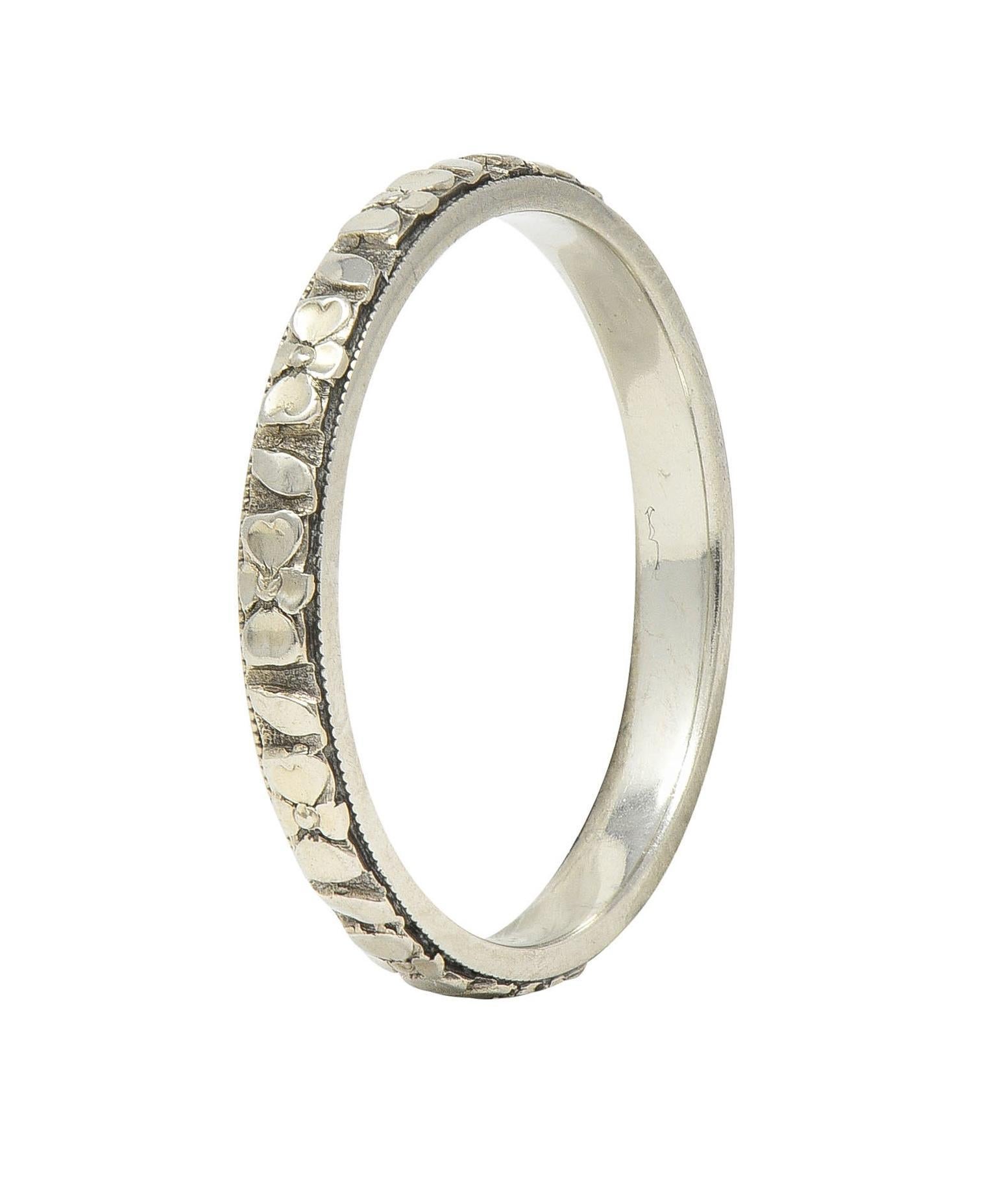 La bague est ornée d'un motif de fleur d'oranger en relief sur tout le pourtour.
Accentué par des bords à détail de milgrain
Estampillé pour l'or 18 carats
Avec la marque du fabricant 
Circa : 1930s
Taille de la bague : 6 3/4 et pas de taille
Mesure