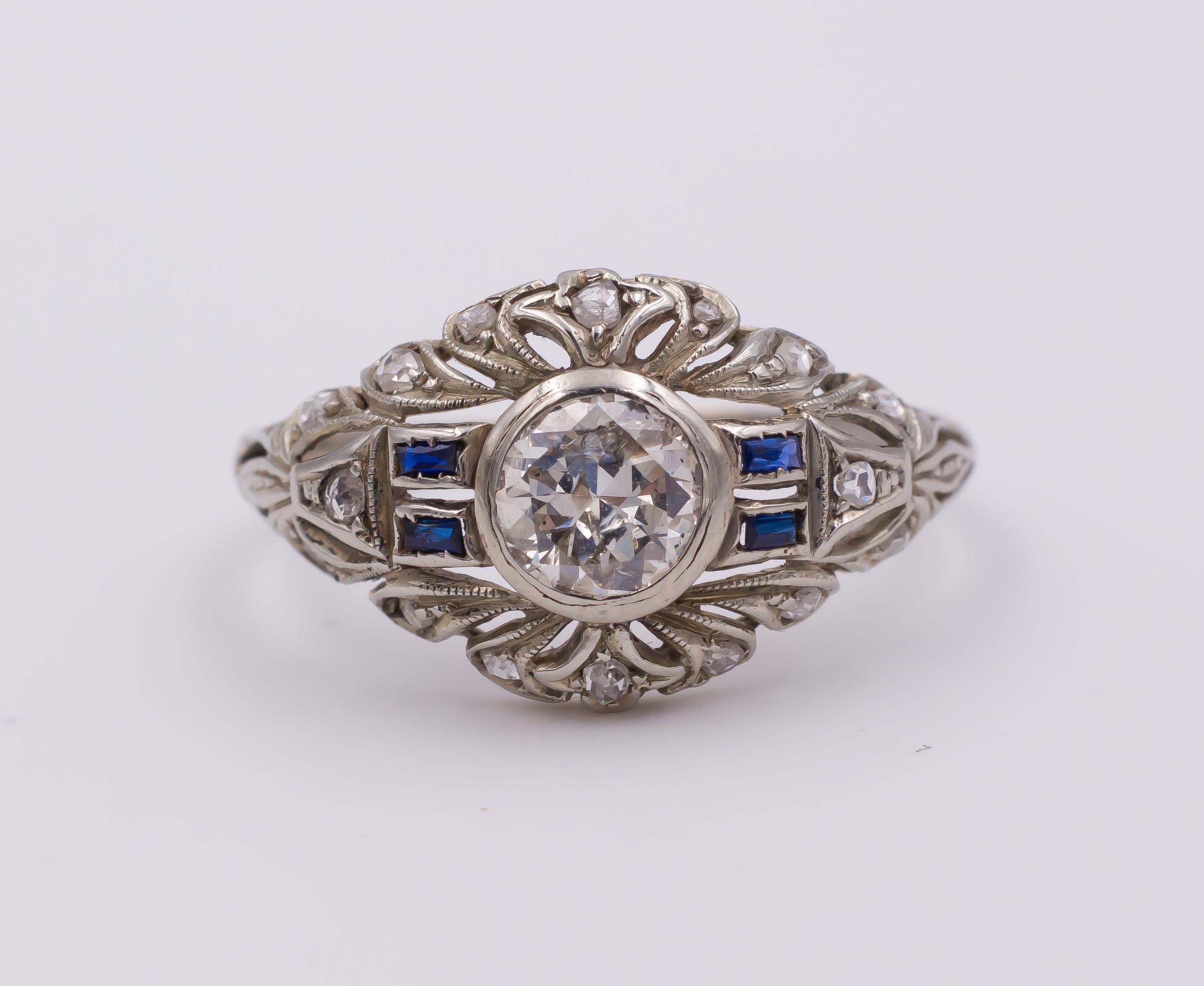 This stunning ring, dating from the 1930s, is a fine example of the Art Deco style: it is set with a central 0.6ct ca. diamond, flanked on either side by two rectangular sapphires; the rest of the head ring is decorated with rose cut diamonds, set
