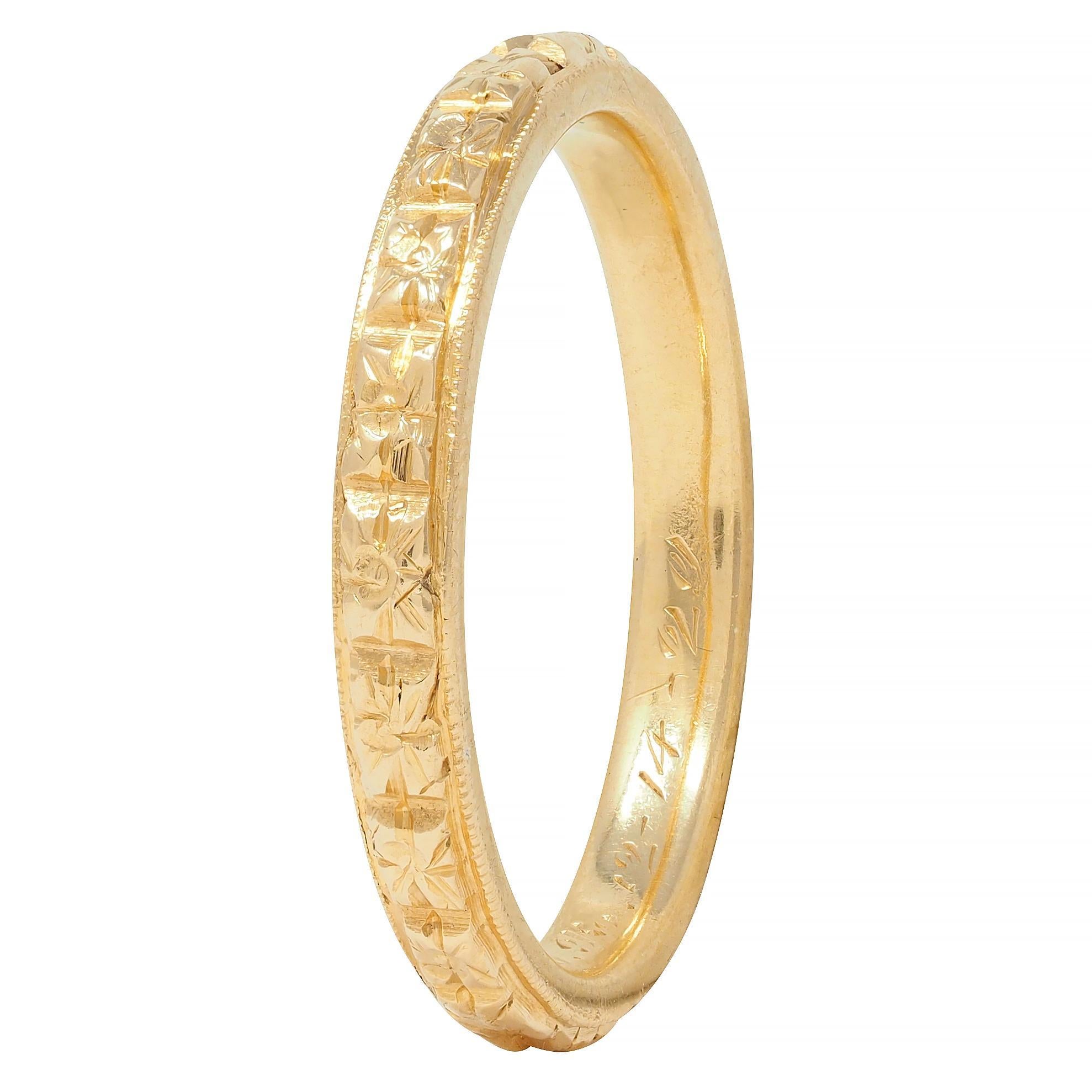 Designed as a band ring with a raised orange blossom motif fully around
With milgrain detail edges and engraved details
Inscribed 'E.D.W. to M.O.B. 12-14-29'
Stamped for 18 karat gold
With maker's mark
Circa: 1920's; via dated inscription 
Ring