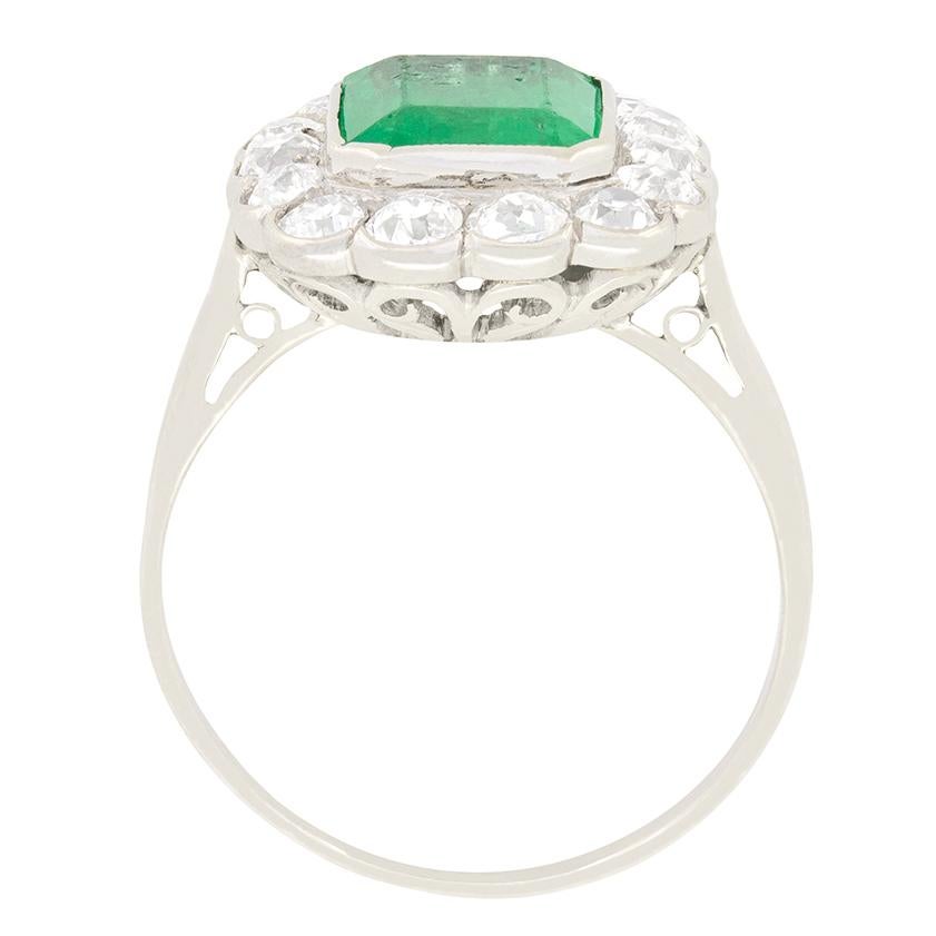 This eye catching cluster ring from the Art Deco period featured a luscious green emerald at its centre, surrounded by a halo of old cut diamonds. The emerald cut central stone is 1.80 carat in weight and has been run over set into the platinum