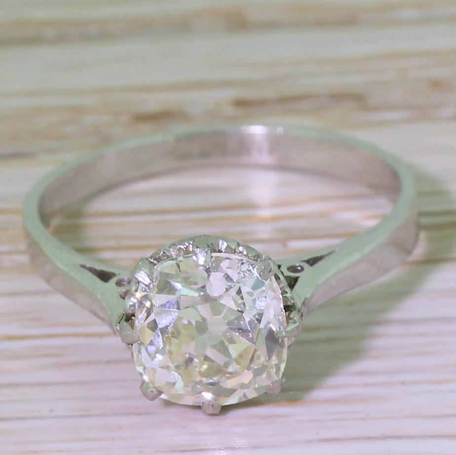 A classic. The large, lively and internally clean cushion shaped old mine cut diamond displays the softest champagne tone. The solitaire is secured in an eight claw collet with heart detailing in the gallery, leading to a slim and flat shank. 