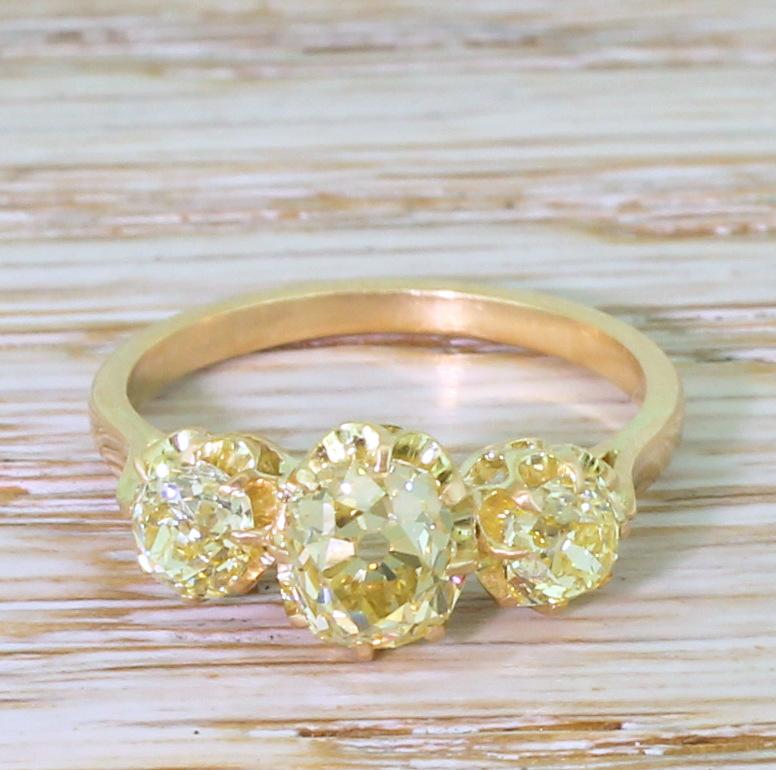 A glowing trio of fancy yellow old cut diamonds. The centre stone, of approximately 1.03 carat, is a fancy intense greenish yellow and flanked by a pair of fancy intense yellows. These impressively glistening stones are each set in eight-claw