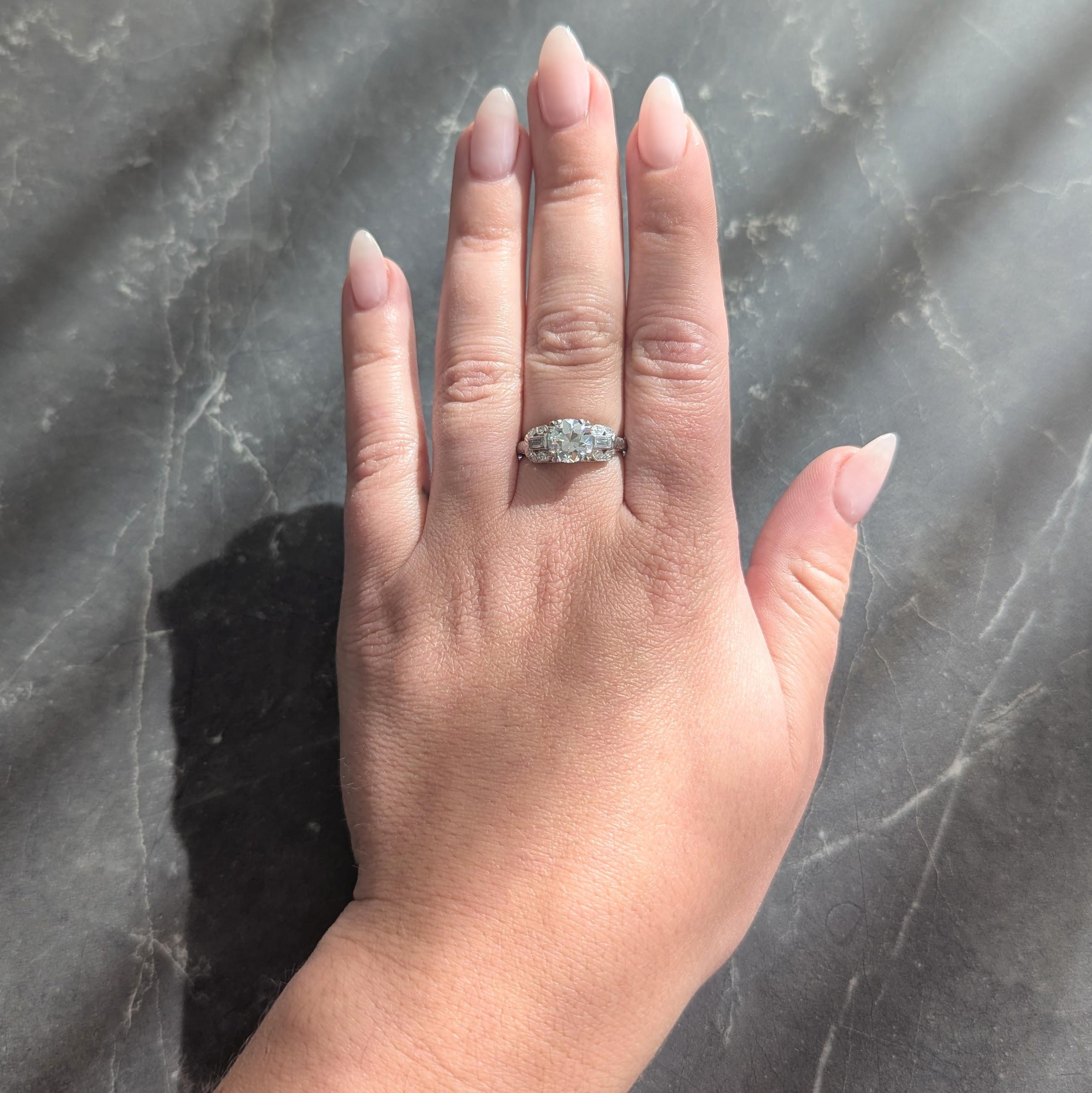 In der Mitte ein Diamant im alten europäischen Schliff mit einem Gesamtgewicht von ca. 1,58 Karat - Farbe I und Reinheit VS
Mit dreifach geteilten Zacken in einem quadratischen Kopf und flankiert von Diamanten im Baguetteschliff
Mit einem