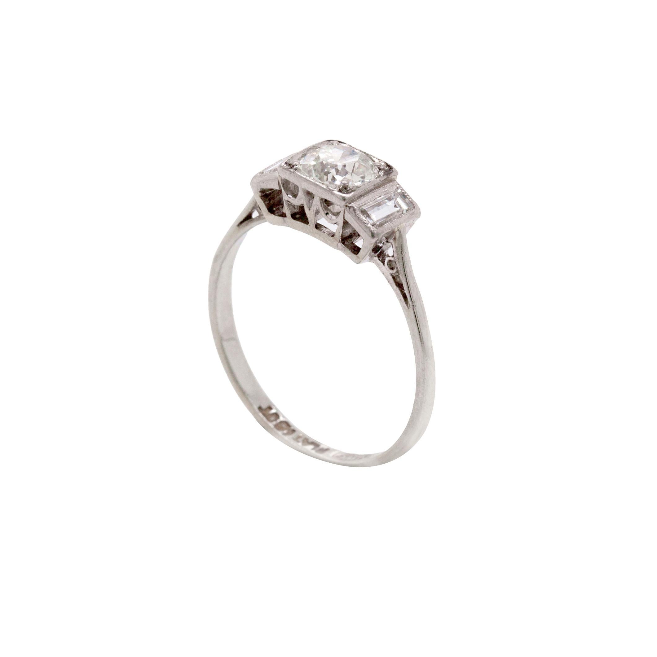 This captivating Art Deco ring is elegant in the simplicity of its design. A stunning Old Mine Cut Diamond in the centre weighs 0.56 carats, and is set in a beautiful square grain setting. It is accompanied by a gorgeous baguette cut to either side