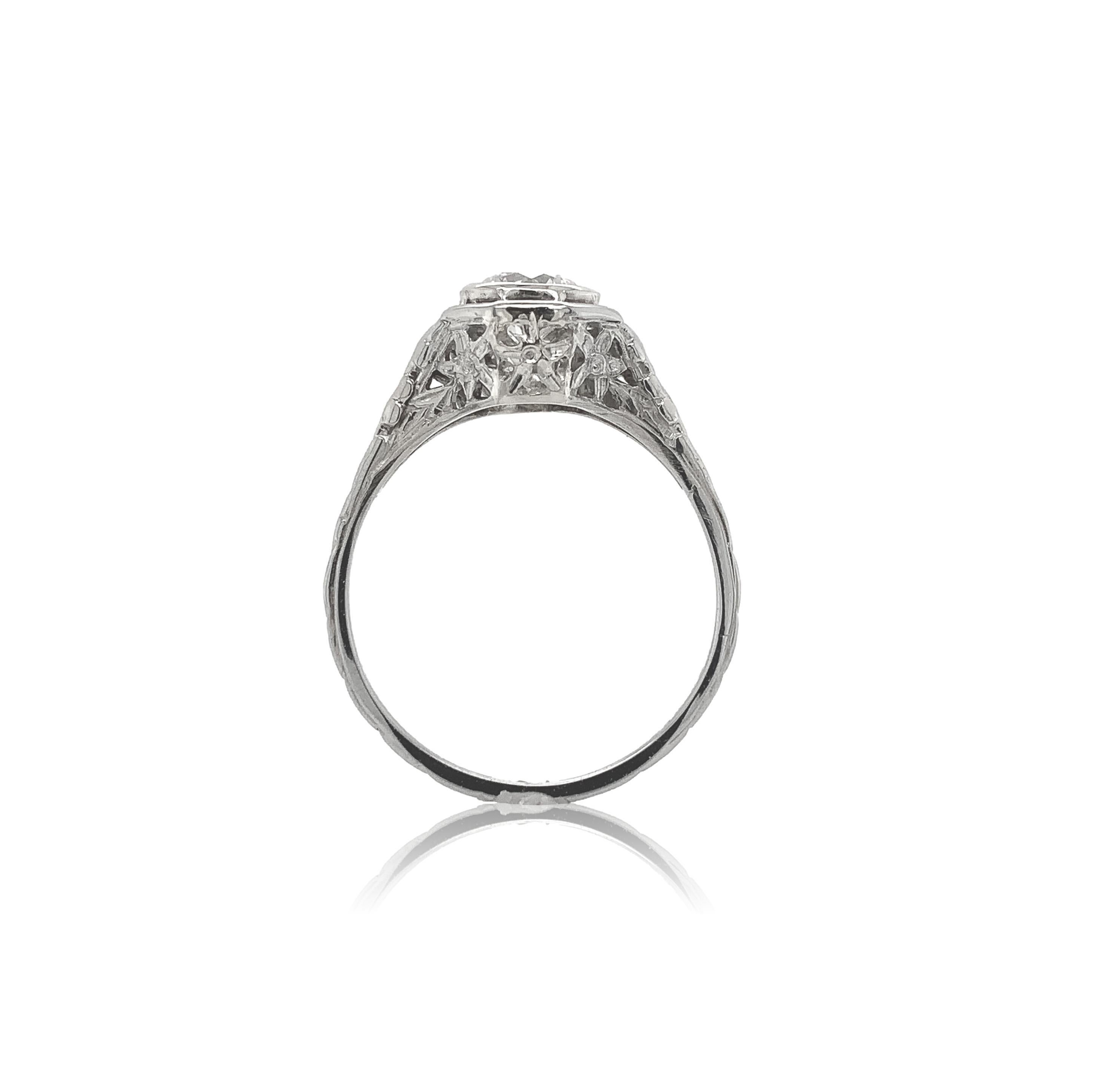 18K white gold filigree .60ct diamond ring. The round brilliant cut diamond has I1 clarity and G-H color and measures about 5.3mm. The diamond is set in a new bezel. The filigree has 3 flowers on each side. The ring fits a size 6 finger, weighs