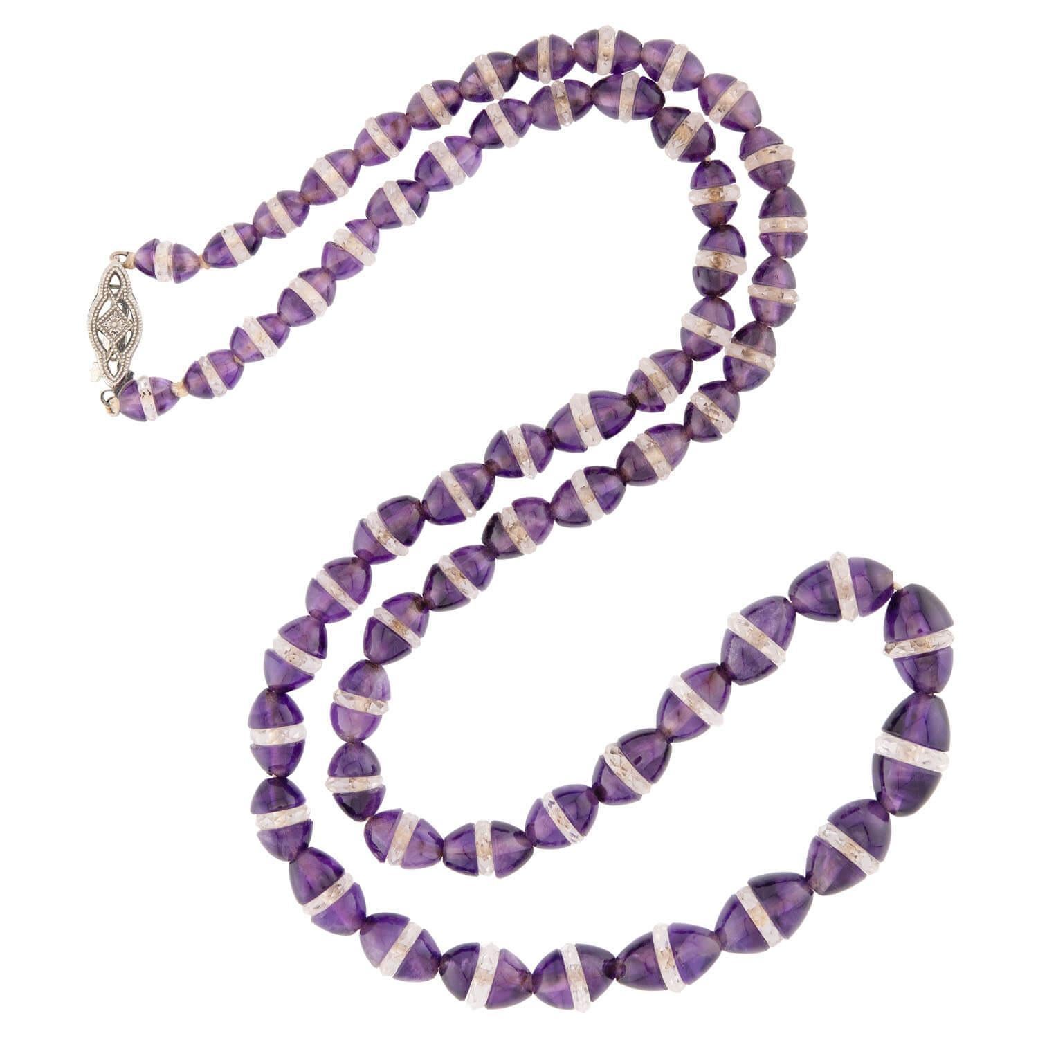 Una bella collana di ametista con perline dell'epoca Art Deco (ca. 1930)! Questo splendido pezzo è composto da un filo di 63 perline di ametista, divise al centro e separate da rondelle di cristallo di rocca sfaccettato. Ciascuna sezione di perline