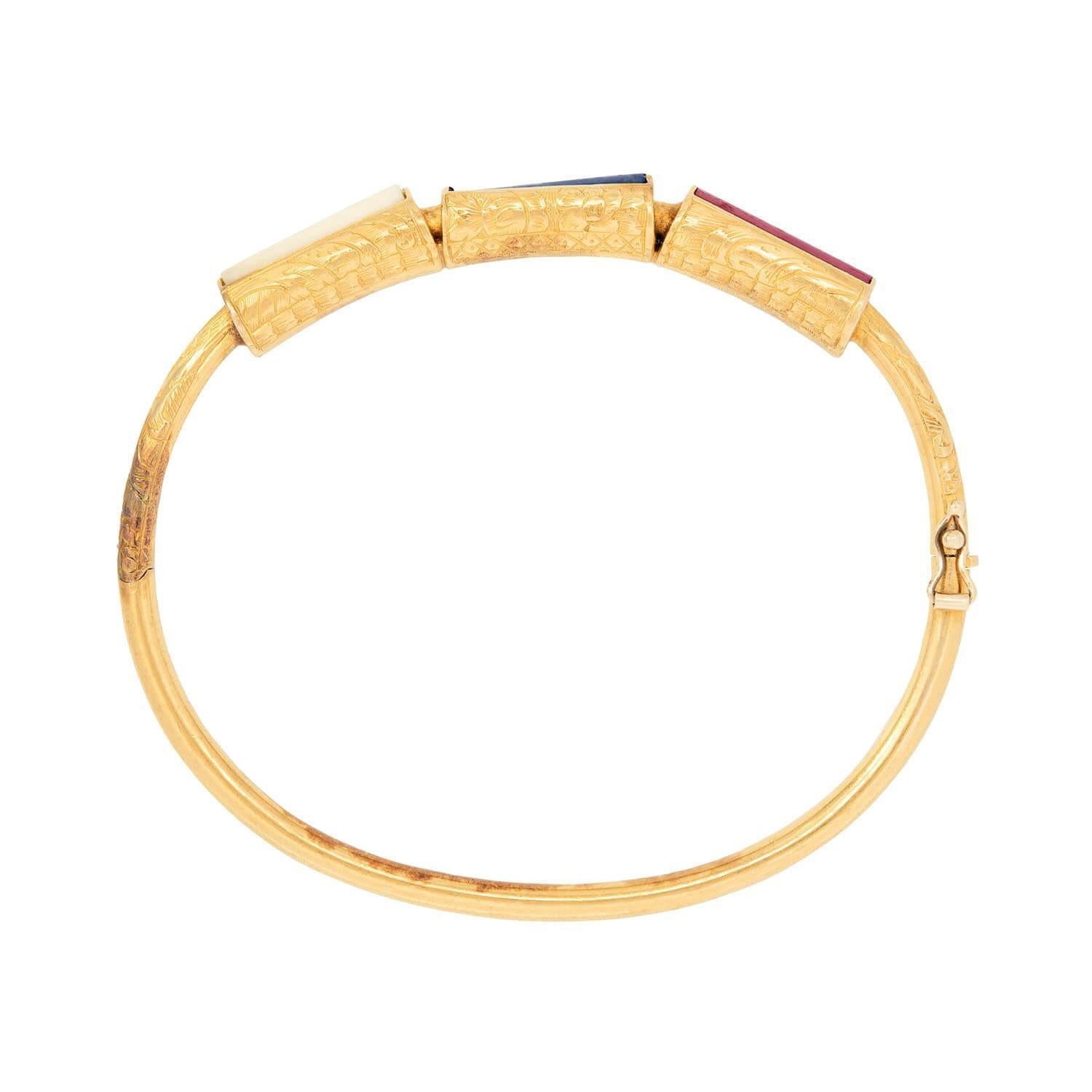 Impresionante brazalete de hueso, lapislázuli y jaspe de la época Art Déco (hacia 1920). La pieza está elaborada en vibrante oro amarillo de 18 quilates y presenta tres componentes cilíndricos con incrustaciones de hueso, lapislázuli y jaspe. Los