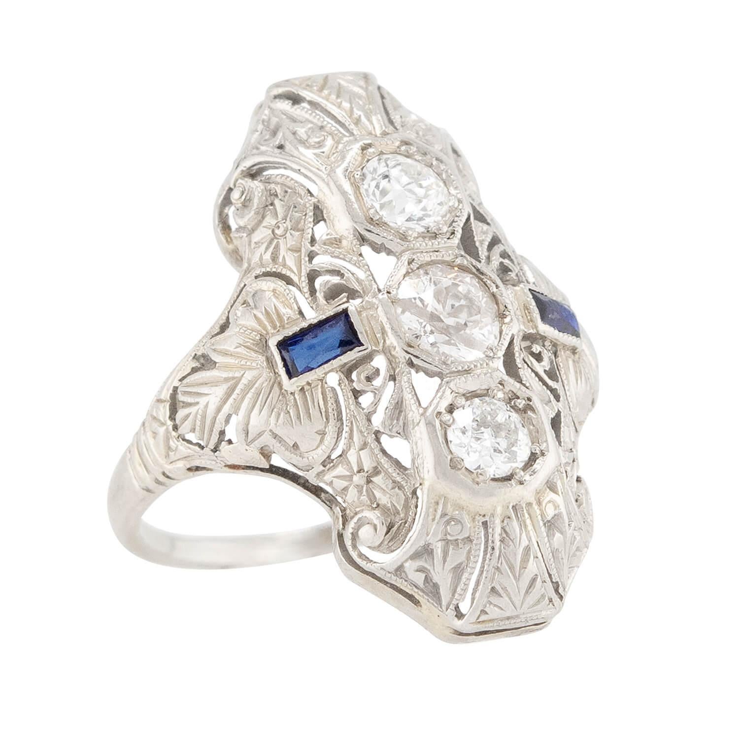An absolutely exquisite navette ring from the Art Deco (ca1920s) era! Crafted in 18k white gold, this ring features a substantial navette-style centerpiece. Three bead-set mine cut diamonds run vertically down the surface of the centerpiece, and