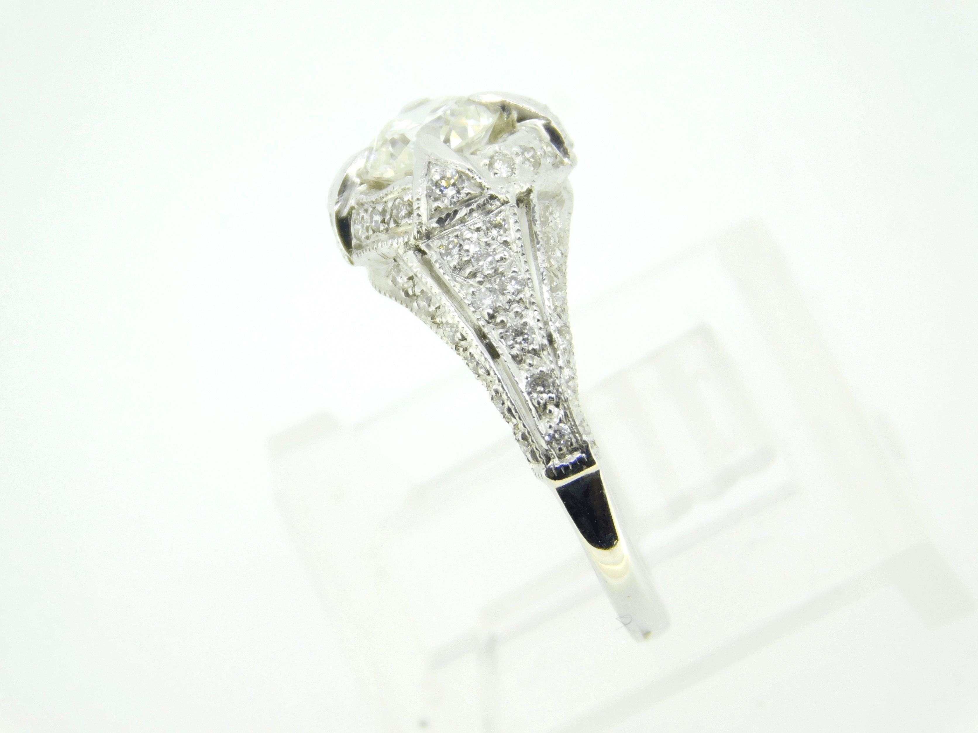 Art Deco 18K white gold 1.05 carat total weight diamond ring featuring a .67ct round brilliant cut diamond. The diamond measures about 5.5mm. There are about 50 small round accent diamonds weighing a total of .38cts. The side diamonds range from 1mm