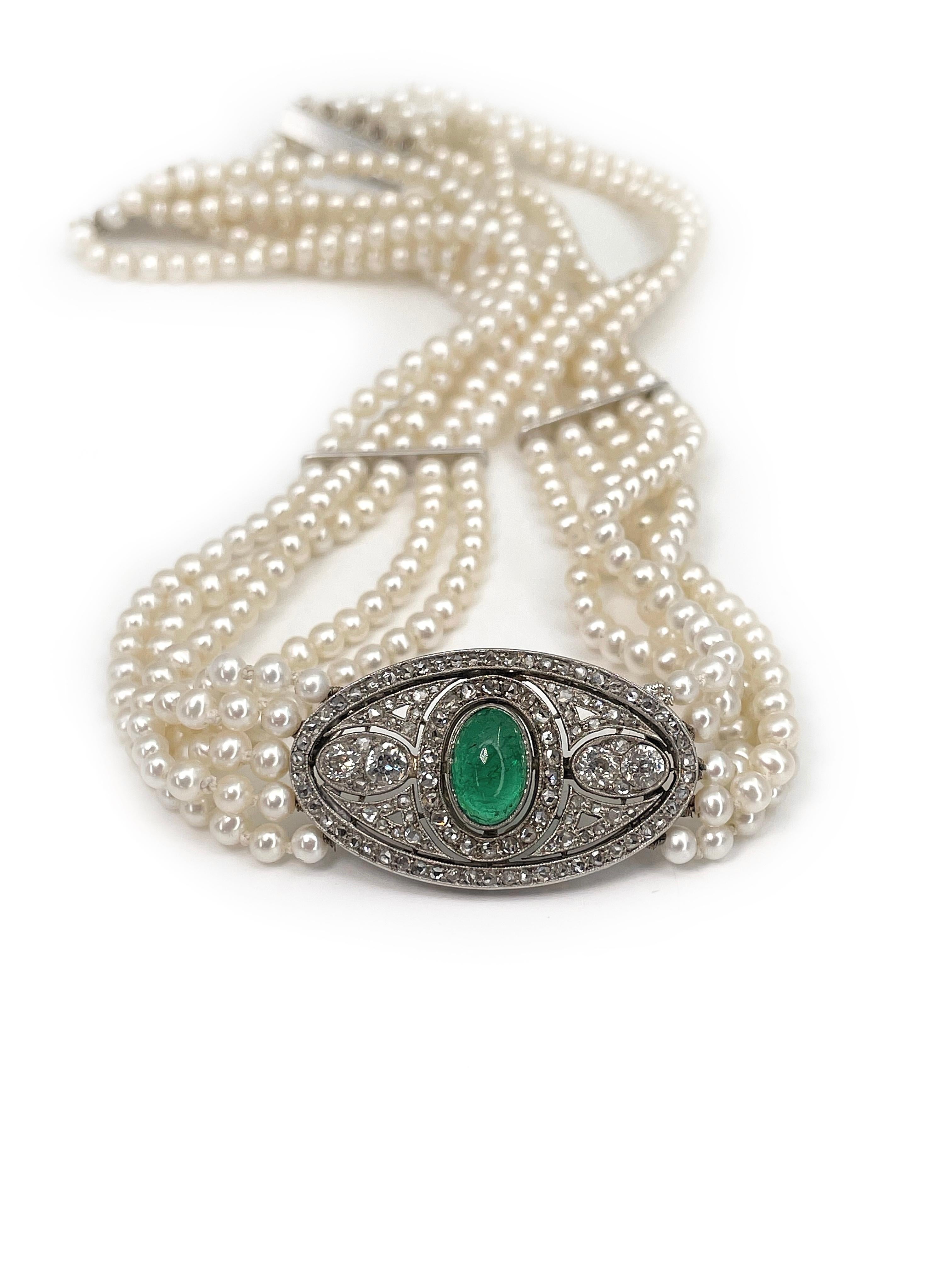 Dies ist eine prächtige Art-Deco-Perlenkette aus 18-karätigem Gold, die mit Platin verziert ist. Das Schmuckstück besteht aus fünf Strängen von Zuchtperlen. 

Das Collier hat in der Mitte ein wunderschönes Detail aus einem Smaragd im