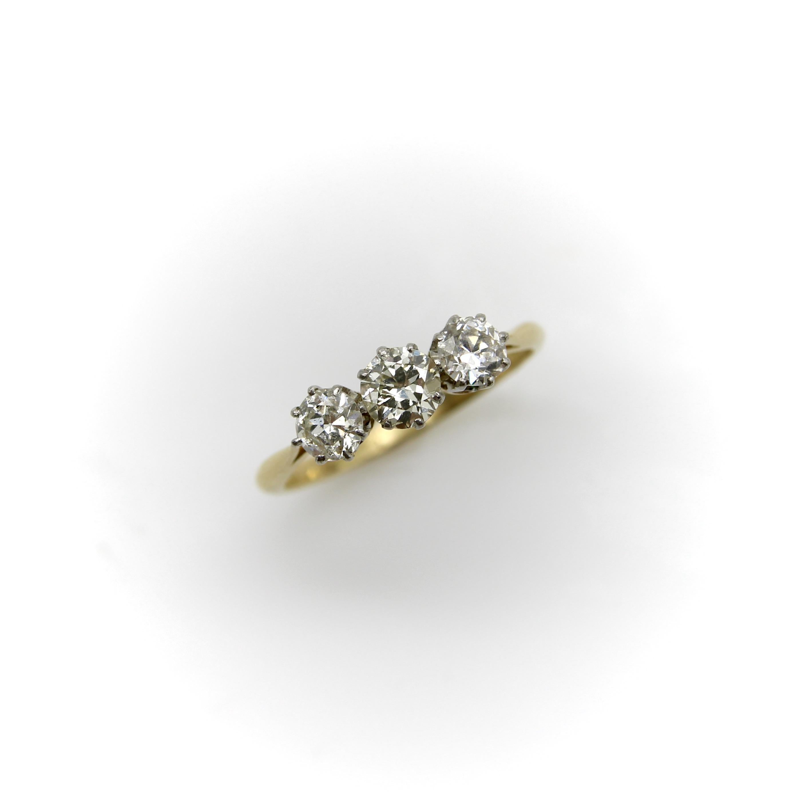 Design classique de l'époque Art déco, cette bague en or 18 carats de belle facture abrite trois diamants de taille Old European sertis dans une monture en platine. La monture est une variante de la couronne, avec des arcs qui se transforment en