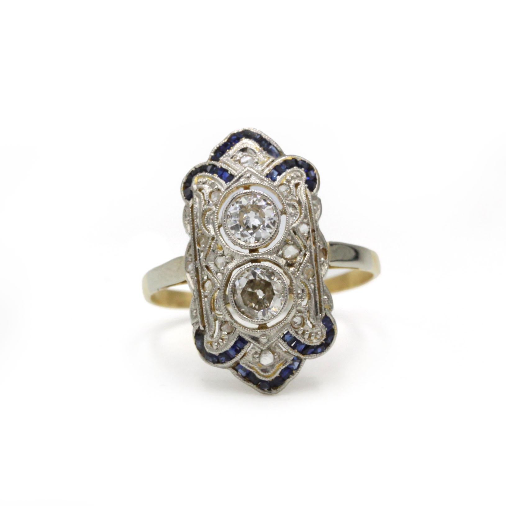 Cette bague Art déco est réalisée en or jaune 18 carats avec une monture en platine et présente un design géométrique raffiné caractéristique de l'époque des années 1920-1930. En son centre, deux diamants de taille européenne ancienne, sertis en