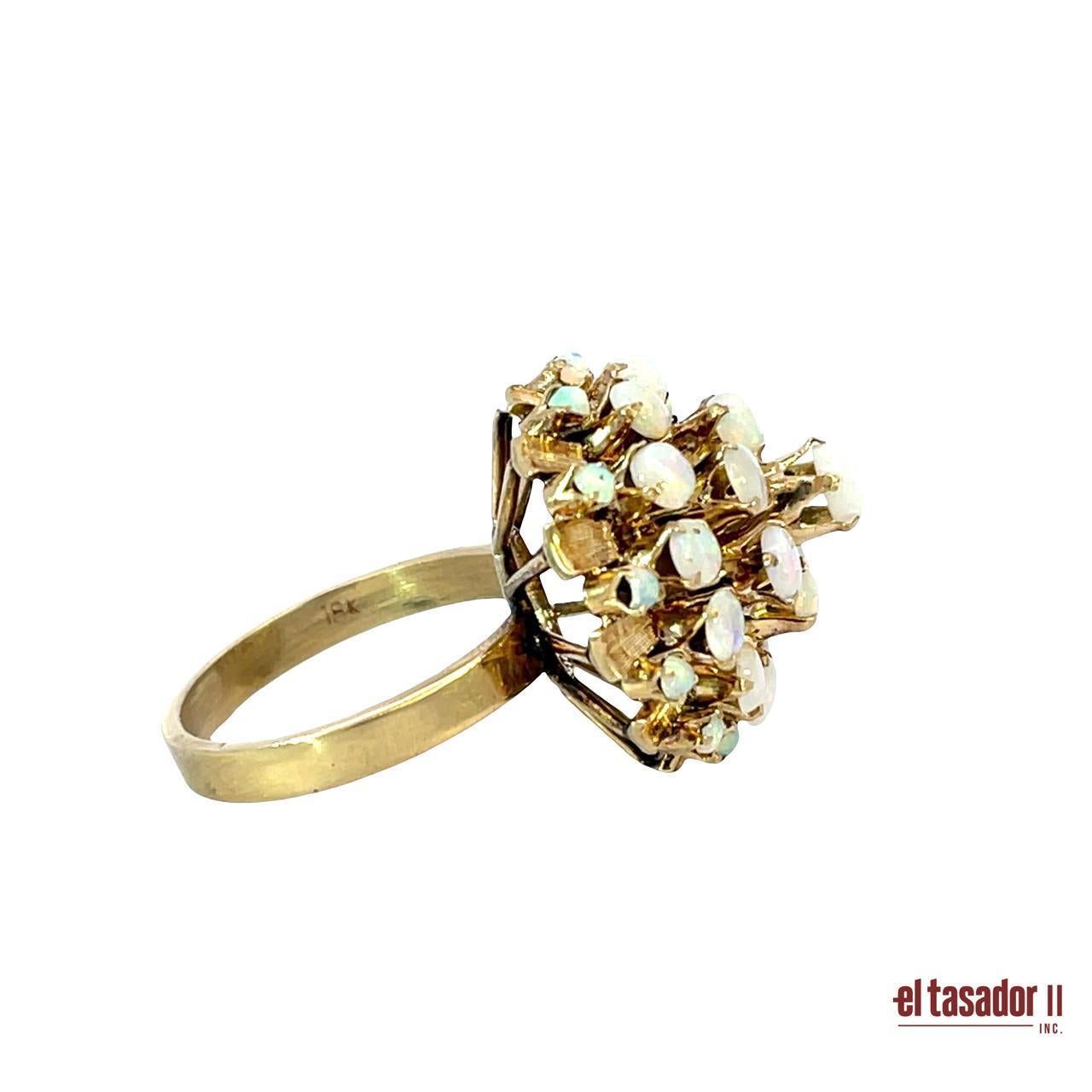 This authentic Art Deco ring is masterfully crafted in rich 18 karat gold, weighing 6.8 grams. The striking dome-shaped design features a cluster of natural opals, each showcasing mesmerizing iridescent flashes of color that shift beautifully in the