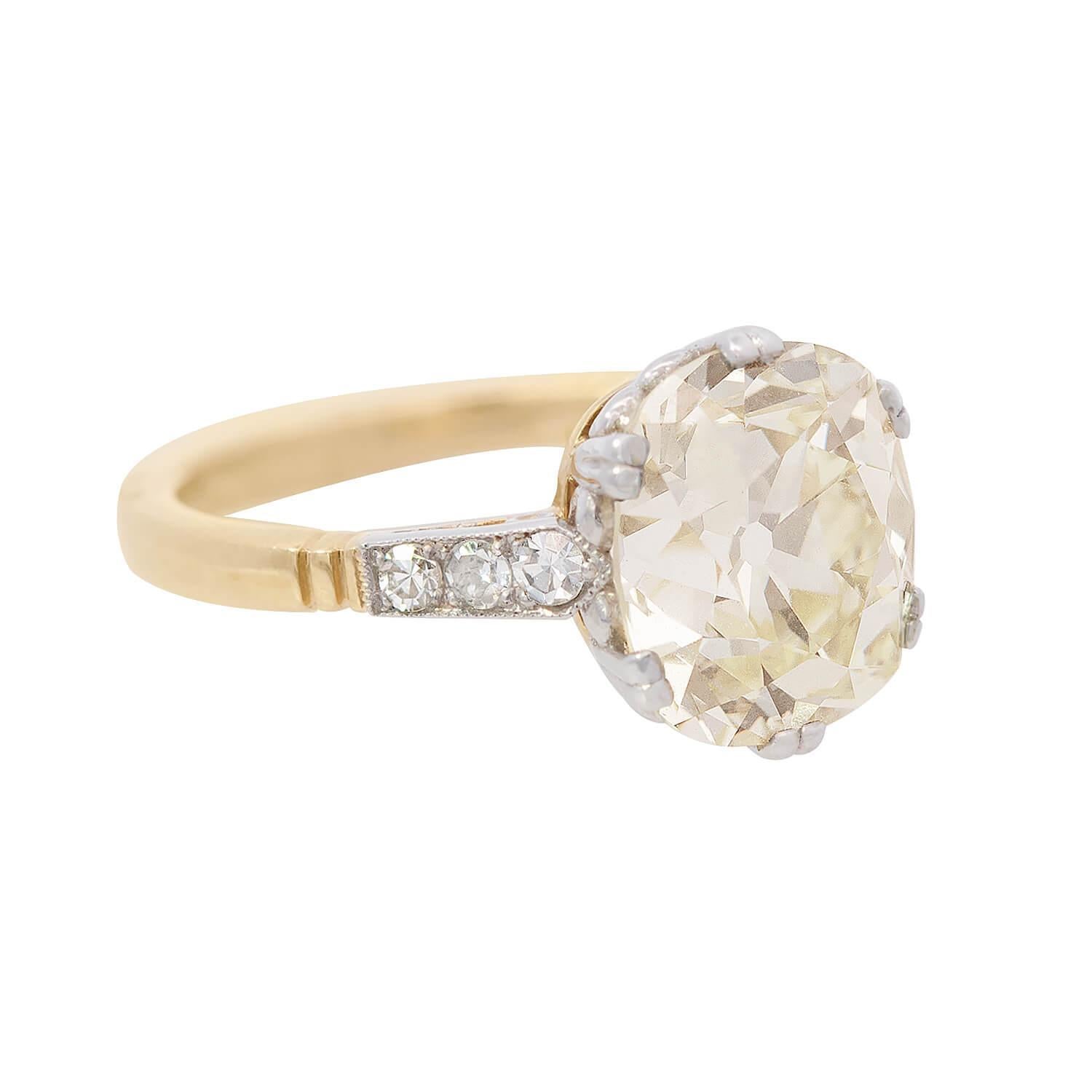 An incredible diamond engagement ring from the Art Deco (ca1930s) era! This stunning piece is crafted in 18k yellow gold and platinum and features an exquisite cushion brilliant cut diamond at the center. The diamond is held within stylish
