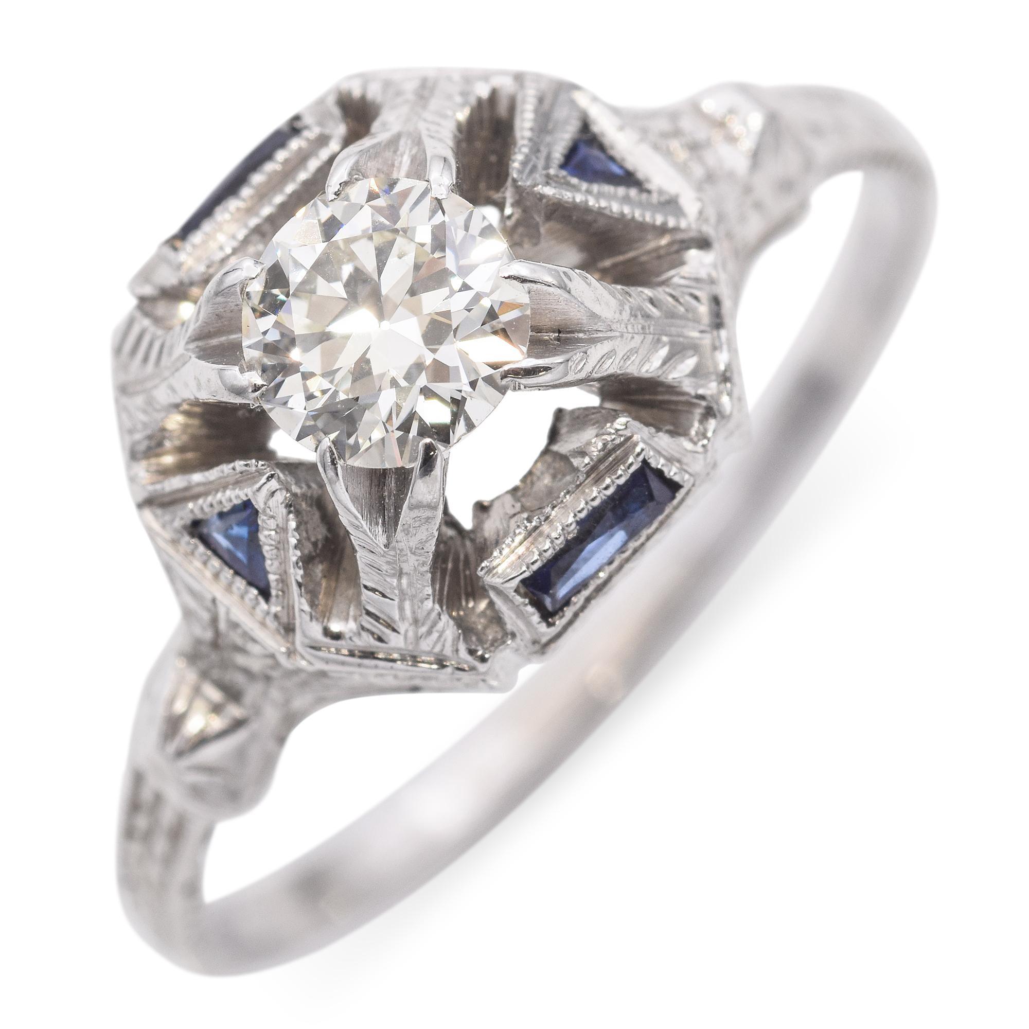 A brilliant round diamond is set within an intricate, openwork design, accented by triangular synthetic blue sapphires in this striking ring.

Weight: 4 grams 
Stone: 0.5ct Transitional Cut Diamond
Stone Grade: L VS1
Measurements: 17 x 10.4 x 6.5mm