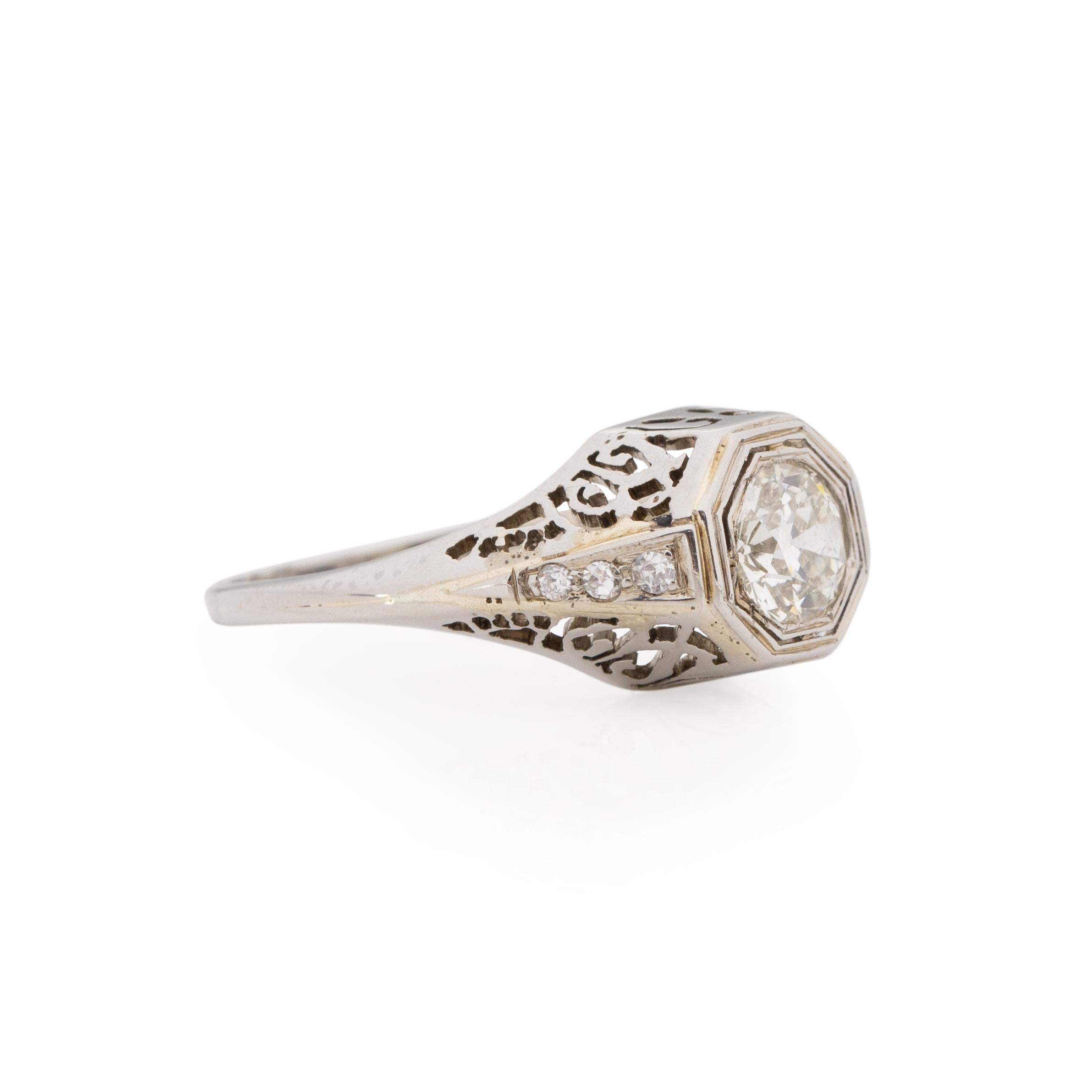 This ring is breathtaking at every angle, crafted in 18K white gold the beautiful .71 Ct center diamond is not only held up by diamond accented shanks but also a delicately carved filigree gallery. This gallery detail allows the center diamond to be