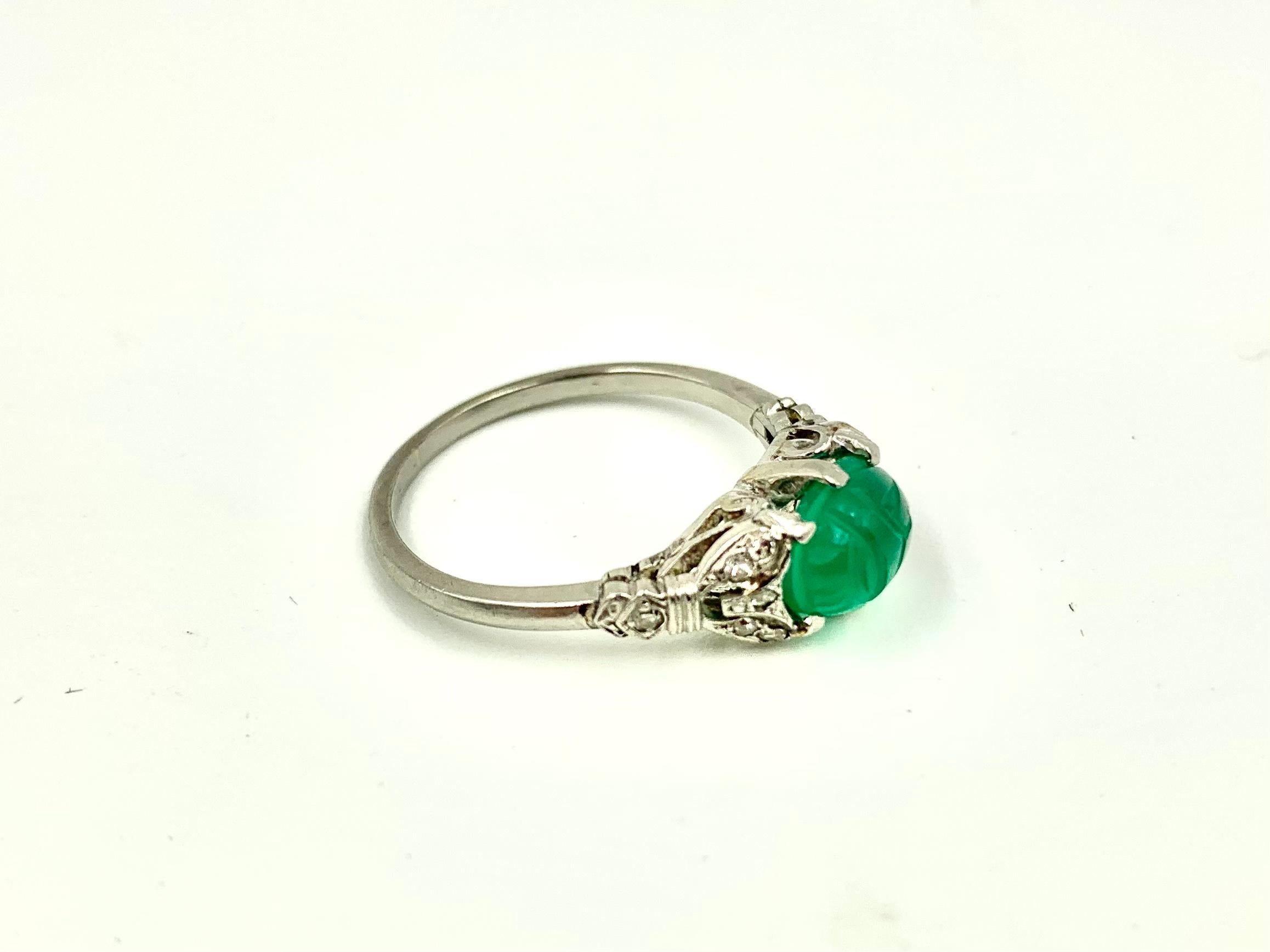 Beautiful Art Deco period 18K white gold, diamond, carved green onyx scarab ring, circa 1920.
Featuring 12 small old-mine cut diamonds, six on each side of the scarab, in an attractive 18k white gold setting.
Makers mark on the interior of band,