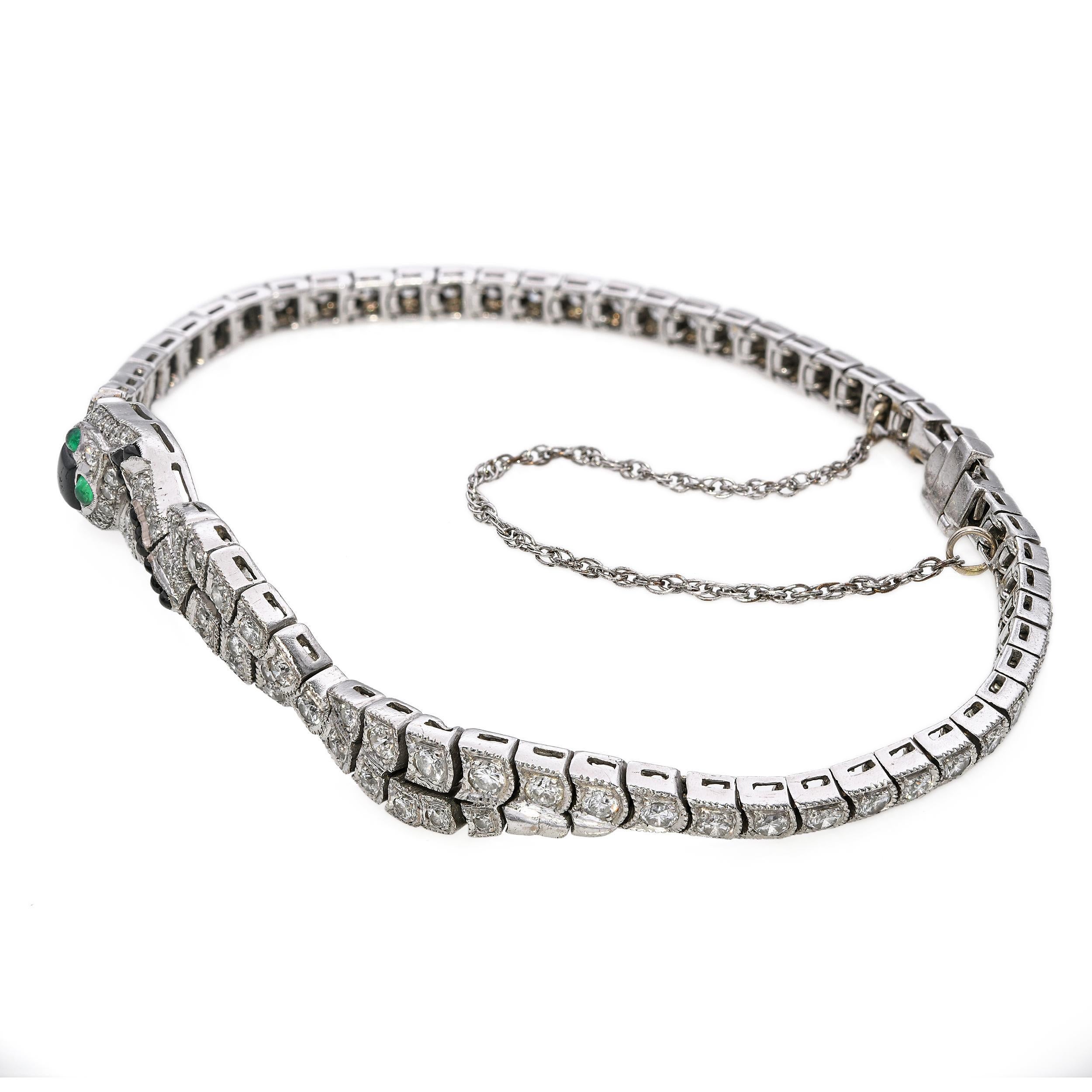 This Art Deco bracelet showcases a mesmerizing snake motif, crafted in 18k white gold and adorned with 2.28tcw of sparkling diamonds. Rich black onyx segments accentuate the sleek, geometric design, while vivid emerald eyes bring the serpent to life