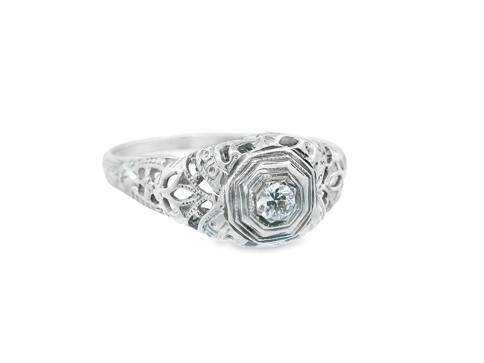 This gorgeous filigree ring was made in 1920's Art Deco period in 18k white gold with a bright white Old European cut diamond in the center. The open filigree design that utilizes negative space make this ring engaging in more ways than one. The