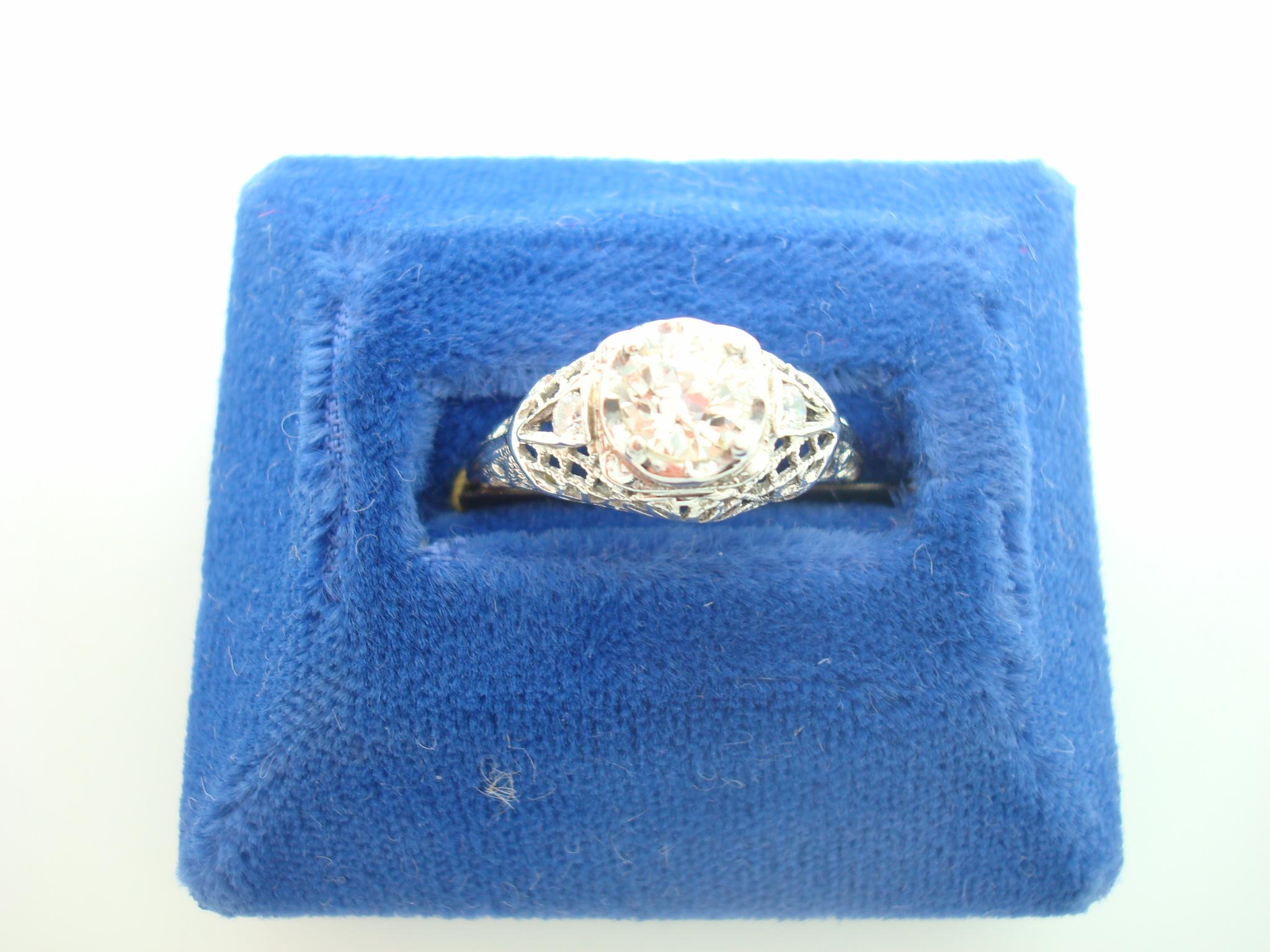 Art Deco 18k White Gold Genuine Natural Diamond Filigree Ring .56ct (#J2360)

18k white gold diamond filigree ring featuring a European cut diamond weighing .56cts. The diamond is accented by two small round diamond accents. The diamonds have fine