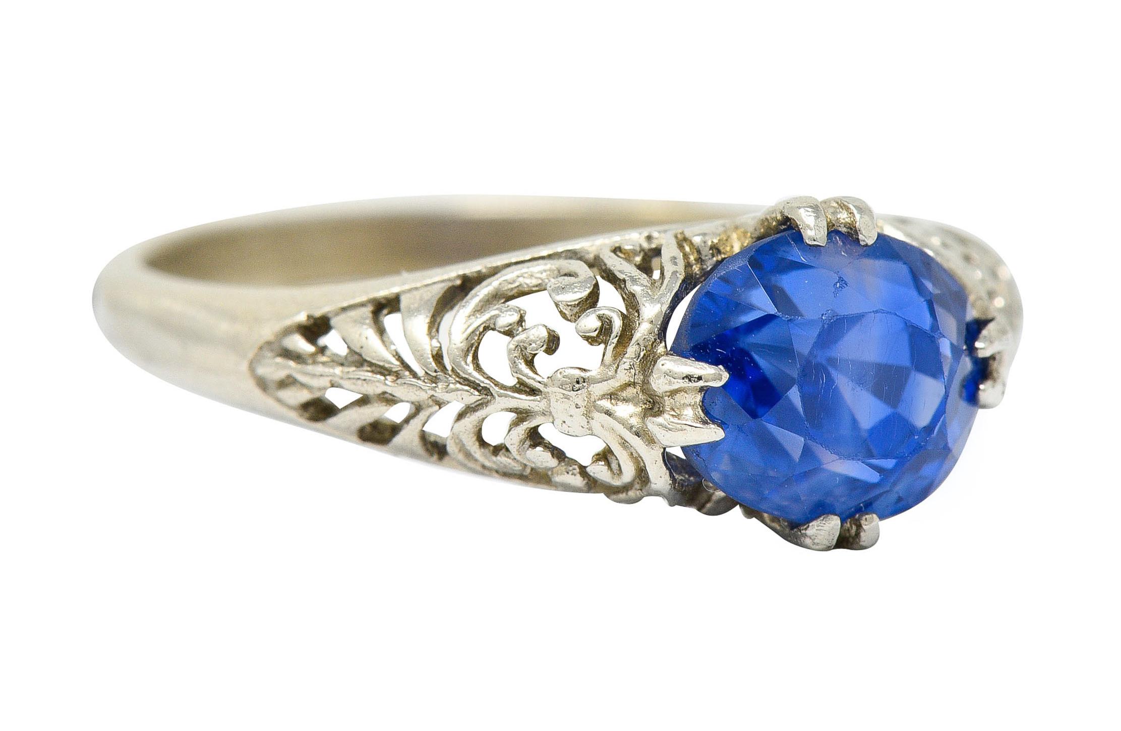Bombè style ring centers an oval cut sapphire weighing approximately 1.90 carats

Translucent and a bright violtish blue color with moderate color banding

Set with split prongs within and elegantly pierced mounting featuring a scrolled foliate