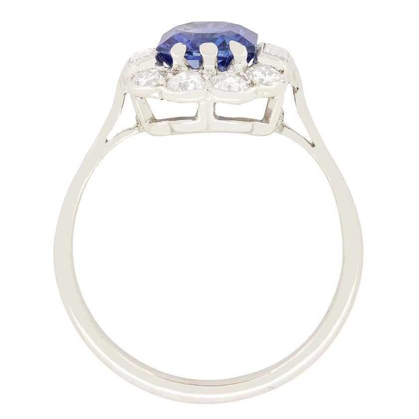 This glamorous Art Deco cluster ring boasts a natural unheated sapphire at it’s centre. The beautiful blue sapphire is an emerald cut stone weighing 1.90 carat. The sapphire is then surrounded by a cluster of sparkling transitional cut diamonds
