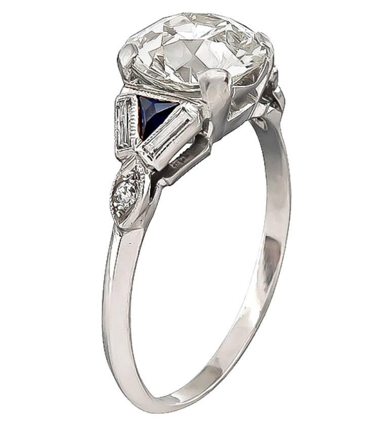This elegant platinum engagement ring from the early 20th century, is centered with a sparkling GIA certified old European cut diamond that weighs 1.91ct. graded K color with VS1 clarity. The center diamond is accentuated by sapphire and diamond