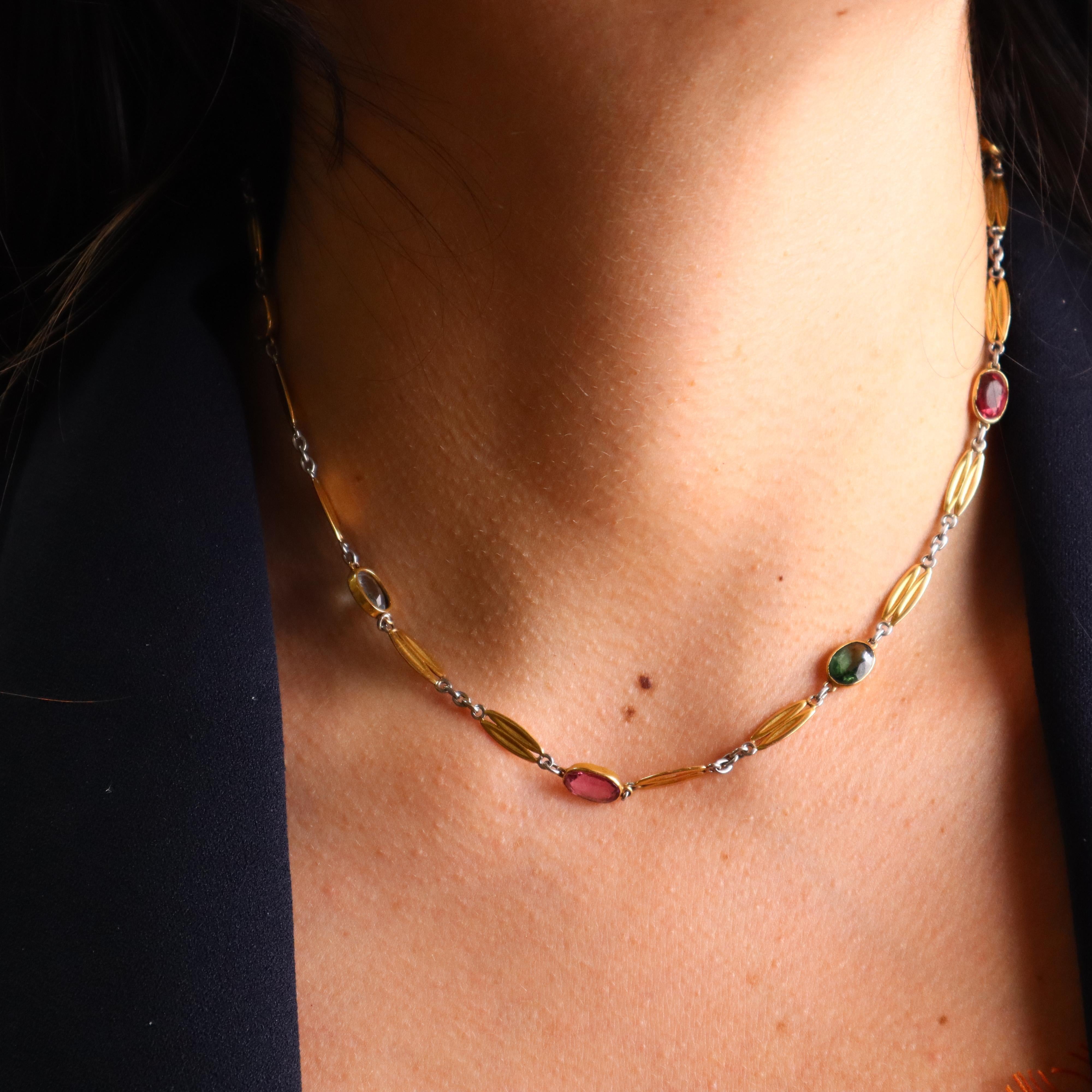 This exquisite circa 1920 Art Deco necklace is a true testament to the elegance and craftsmanship of the era. Expertly crafted in 18k yellow gold and platinum, it features a bezel-set arrangement of oval-shaped natural aquamarines, citrine, and pink