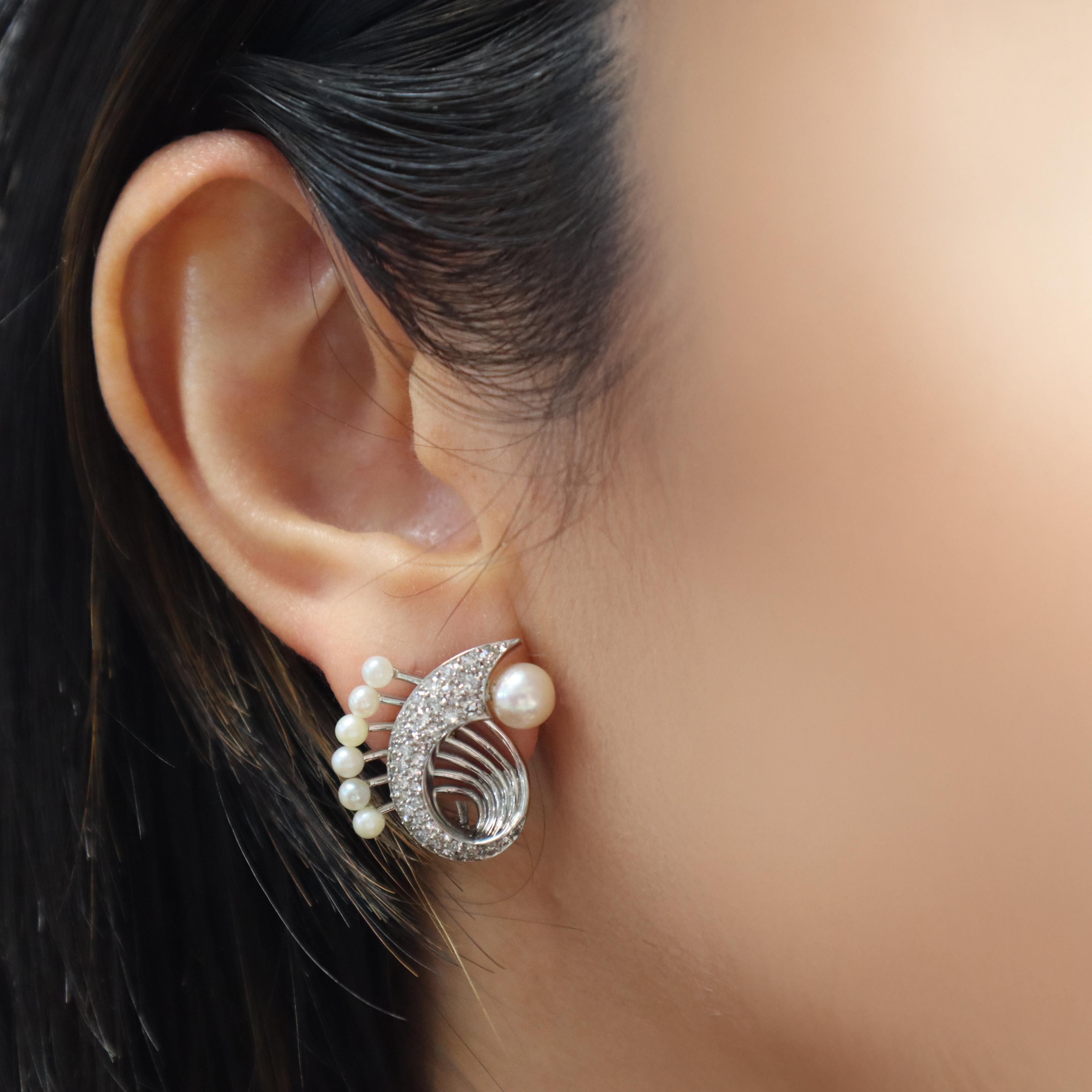 Questi squisiti orecchini Art Déco, realizzati in platino, presentano una splendida combinazione di 14 perle bianche rotonde accentate da un pavé di diamanti a taglio singolo. I diamanti, del peso complessivo di circa 1,30 carati, hanno una