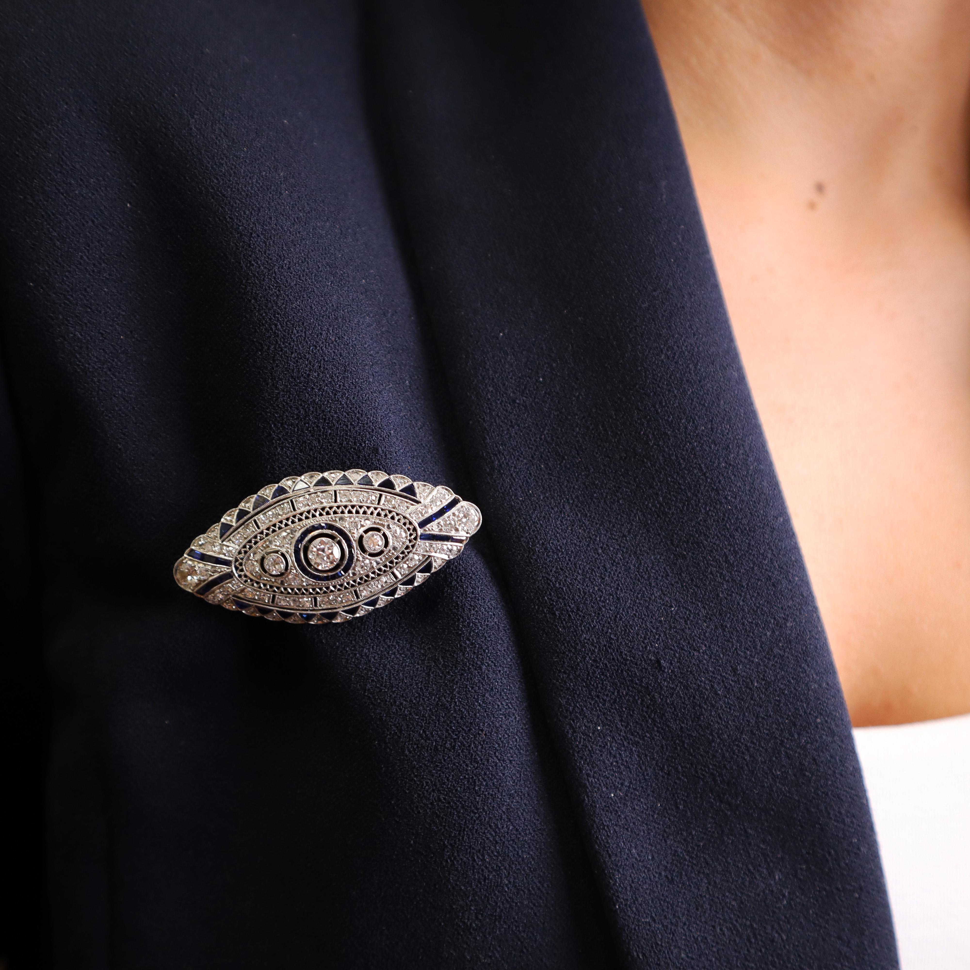 Introducing a stunning circa 1920s Art Deco filigree brooch, meticulously crafted in platinum. This exquisite piece features a captivating European cut diamond at its center, weighing approximately 0.35 carats, with a color grade of G-H and clarity