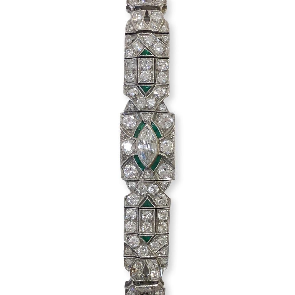 Spectacular authentic Art Deco 1920's bracelet designed in Platinum with milgrain detail. Contains bead set antique round diamonds, one (1) channel set antique marquise cut diamond and twelve (12) natural green emeralds accenting around center