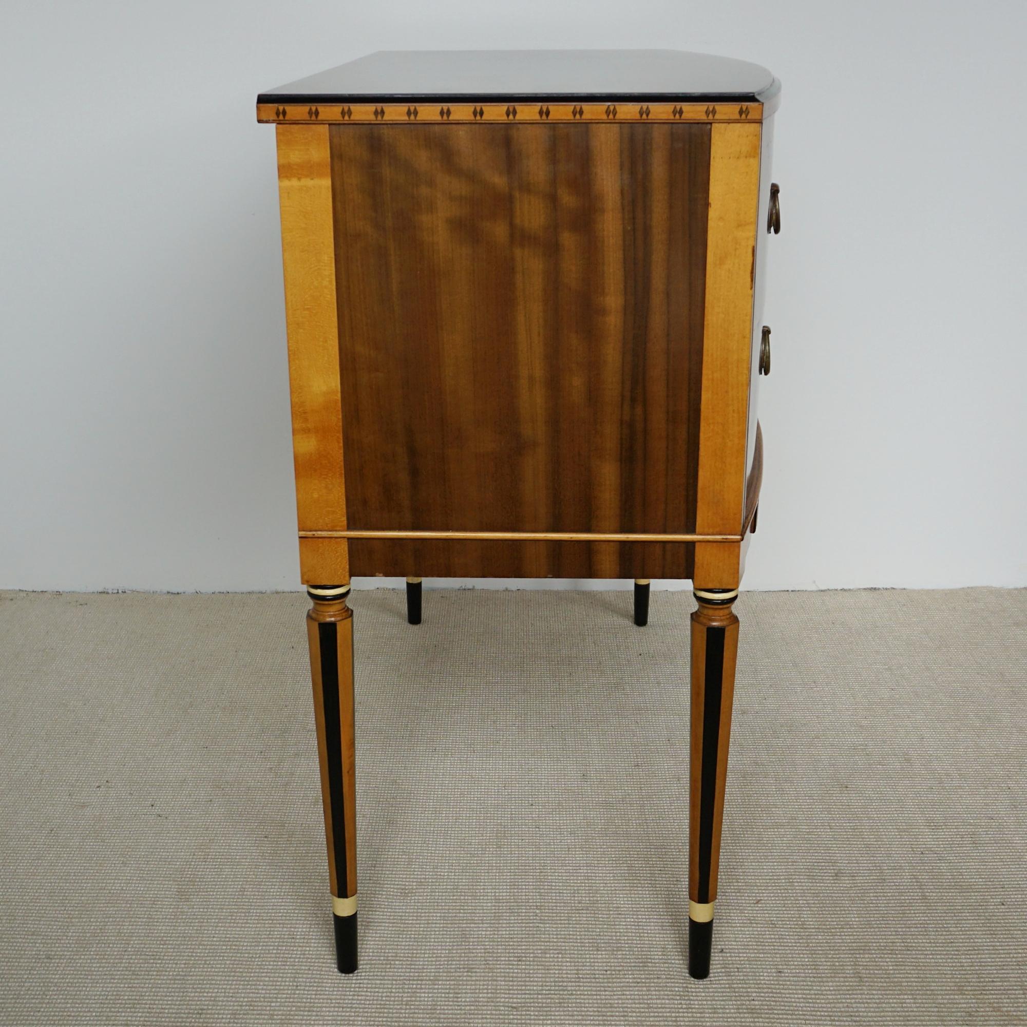 An Art Deco two drawer chest on tapered legs. Australian walnut veneered with ebonised and satinwood inlay and original brass handles with ivorine shell detail. 

All of our furniture is extensively polished and restored where necessary to the