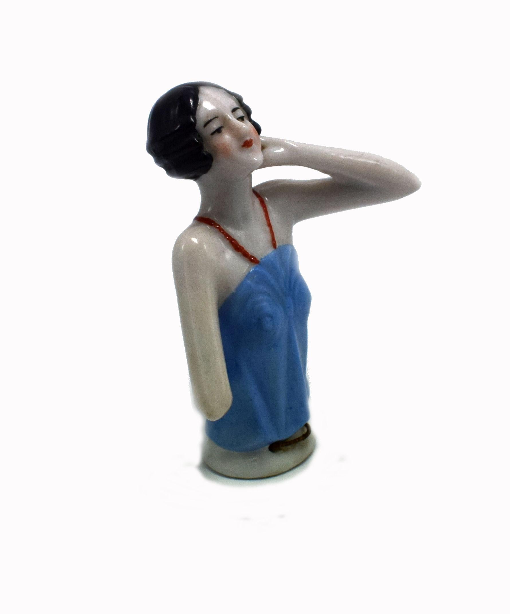 On offer and for your consideration is this charming and totally authentic late 1930s Art Deco German porcelain pin cushion half doll in the form of a pretty flapper girl with a wave black bob hair cut. She's wearing a blue strap top and is