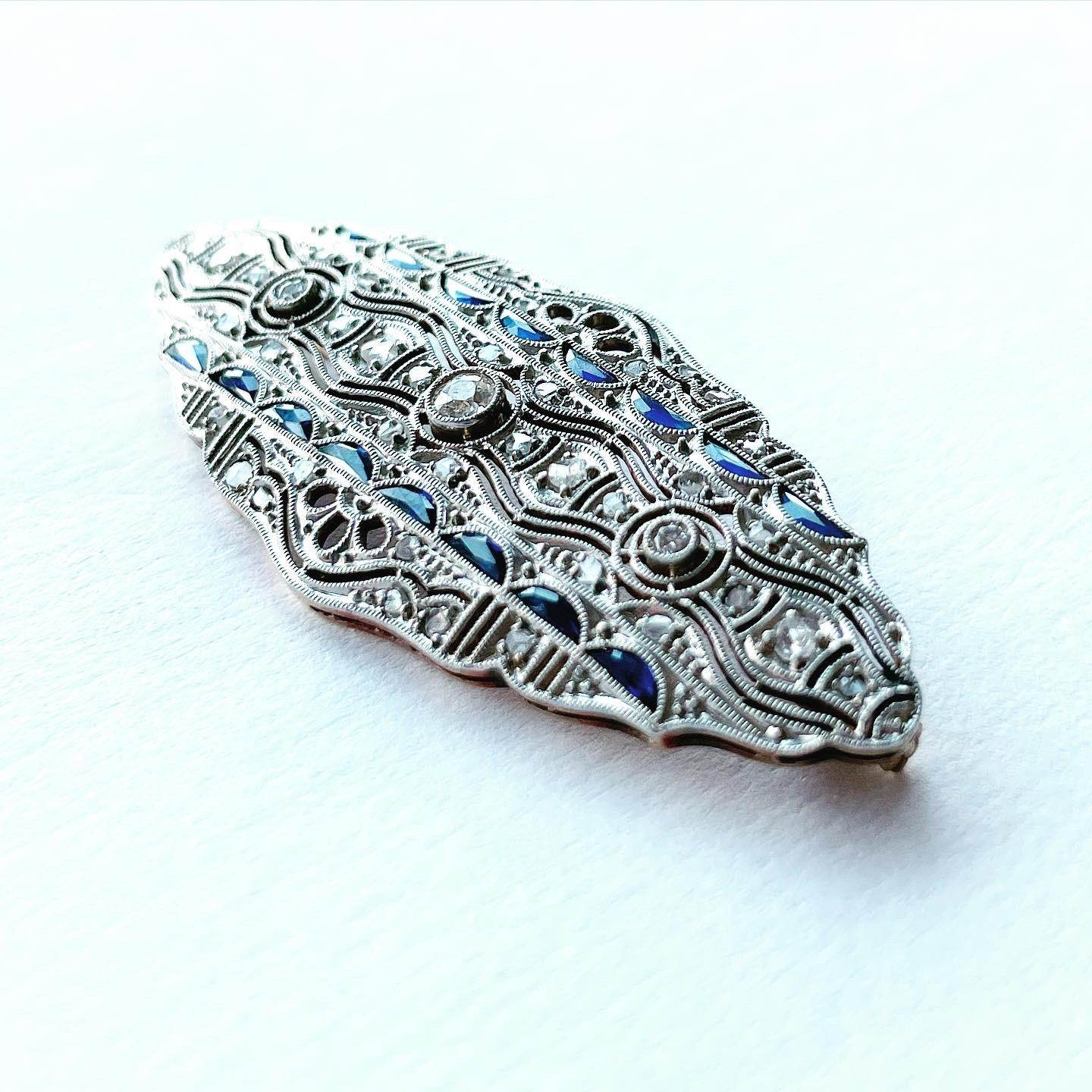 Diese Art-Deco-Brosche mit Diamanten und Saphiren ist der Inbegriff des Deco-Stils. Die Symmetrie, die Geometrie, die antiken Diamanten und Saphire, alles an dieser Brosche ist das, wofür Art-Déco-Schmuck bekannt ist. 

Die Brosche enthält 3 alte