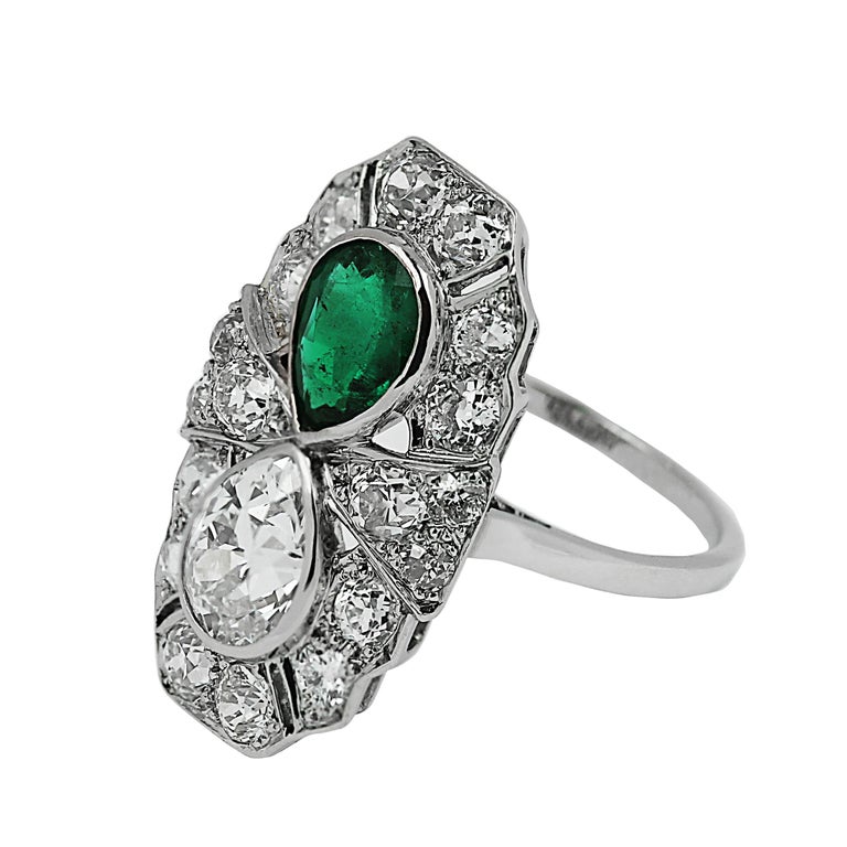 An Art-Deco emerald and diamond ring. This platinum-set ring dates to the 'roaring' 1920s - the Great Gatsby era - an age synonymous with elegance and bold artistic design. It features a beautiful pear-shaped emerald and diamond within a sparkling