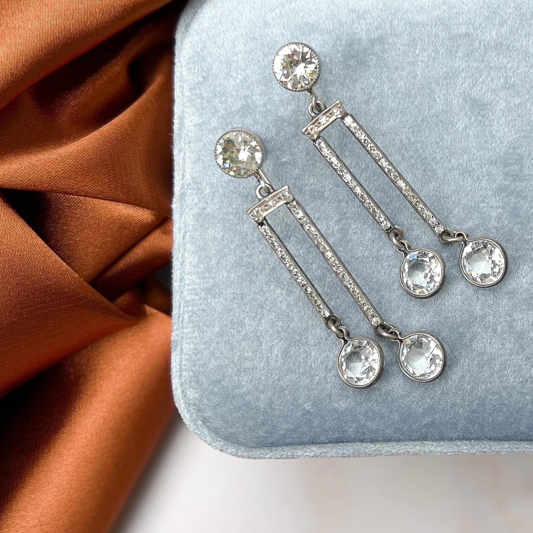 These elegant earrings, featuring shimmering crystal drops, date from the 1920s. 

Condition Report:
Excellent 

The Details...
These earrings are constructed from silver - they are stamped 'STERLING' on the reverse of the design and the reverse of