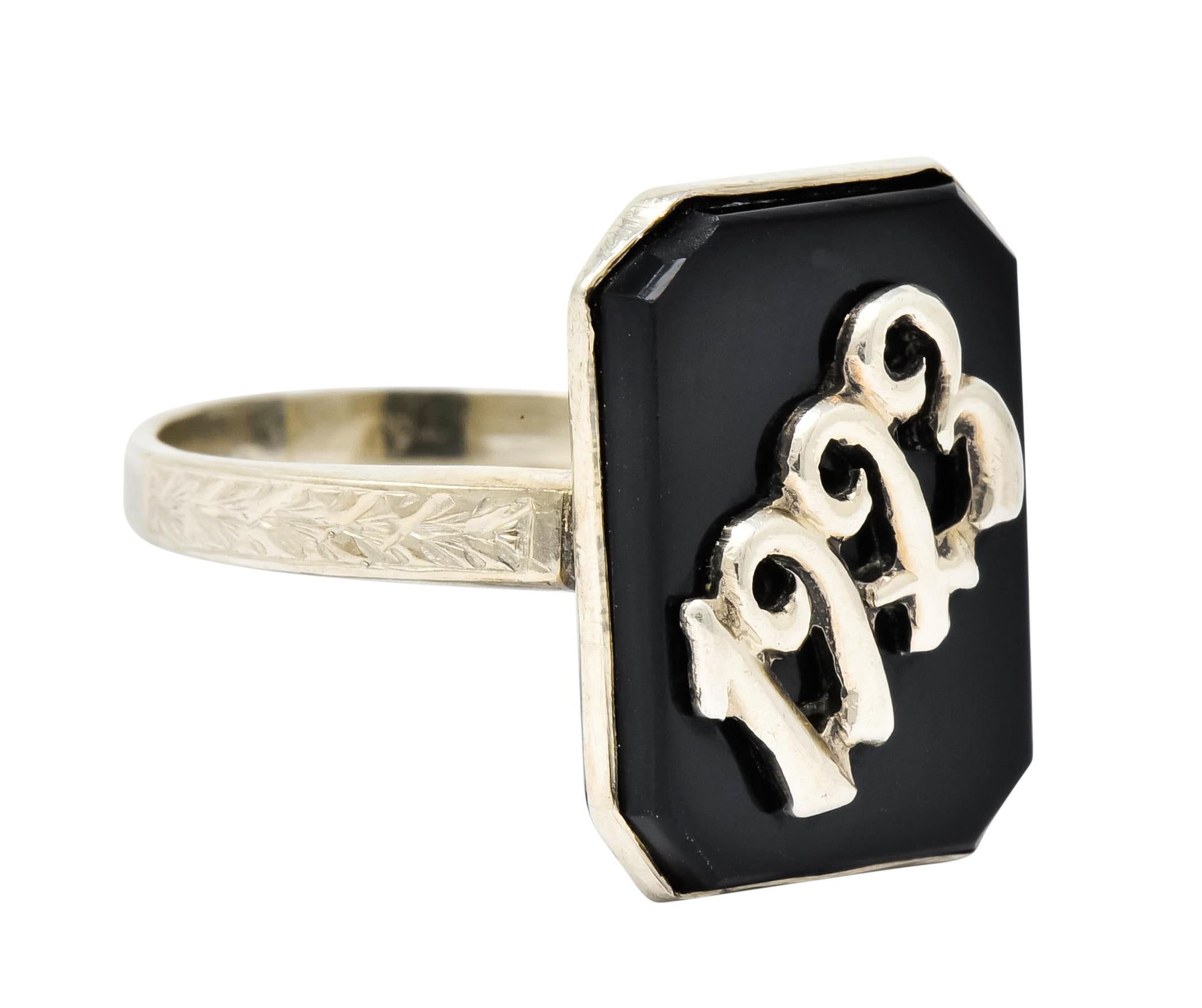 Ring designed as a bezel set octagonal onyx tablet, glossy opaque black in color with excellent luster

Centering the stylized white gold numerals '1923'

Flanked by deeply engraved foliate shoulders

Stamped 14k for 14 karat gold

Circa 1923

Ring