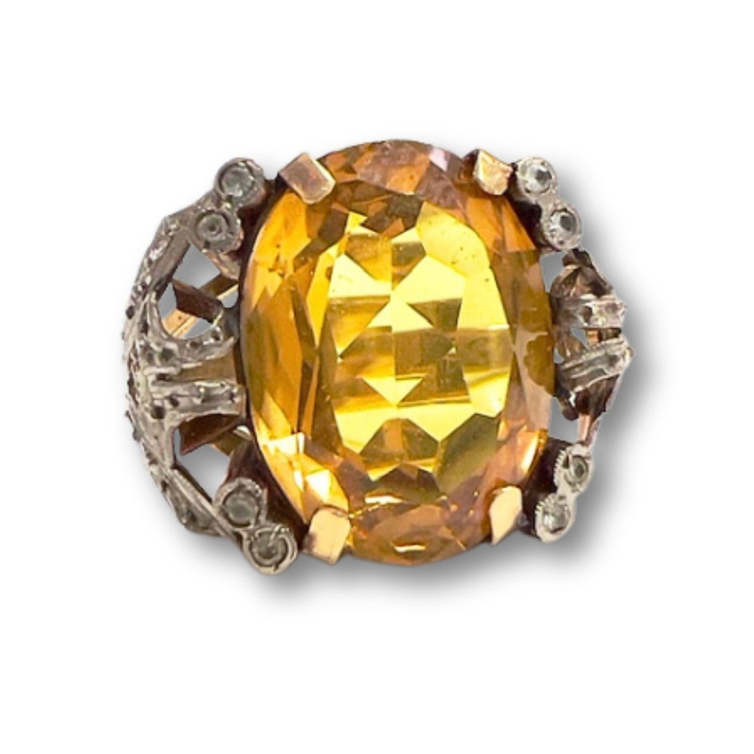 This Art Deco ring from the 1930-1935 period is crafted in 18K gold with platinum accents and features Diamonds and a central Citrine.
 It has a weight of 6 grams and is sized 9/49. 
The Diamonds are simple-cut, totaling 0.20 carats, and are of SI1