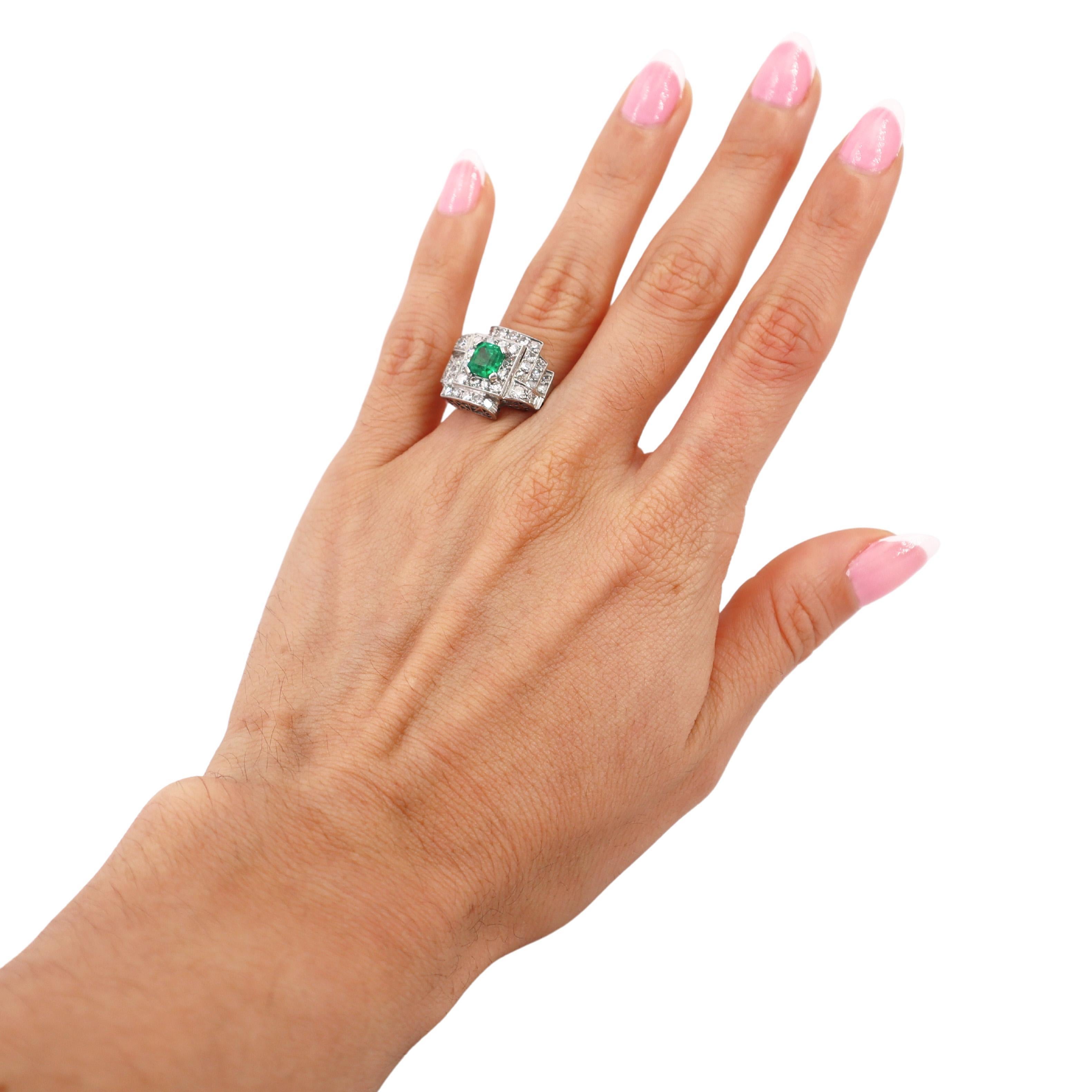 This magnificent Art Deco ring, crafted in 1930, is a timeless representation of the era's sophisticated style and meticulous craftsmanship. Made from platinum, the centerpiece of this ring is a vivid emerald-cut emerald, weighing approximately 1.00