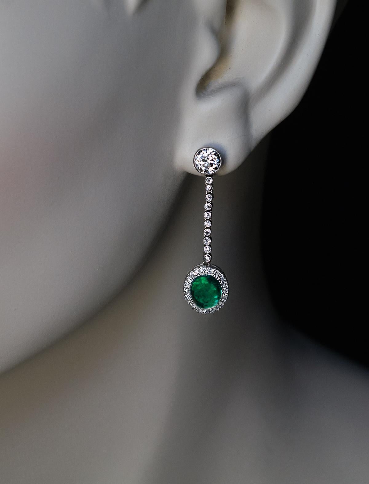 A pair of Art Deco platinum earrings from the 1930s is set with bright white old cut diamonds and two well matched cabochon cut emeralds of an excellent alpine green color with a hint of blue.

The principal two diamonds are 5 mm old European cut